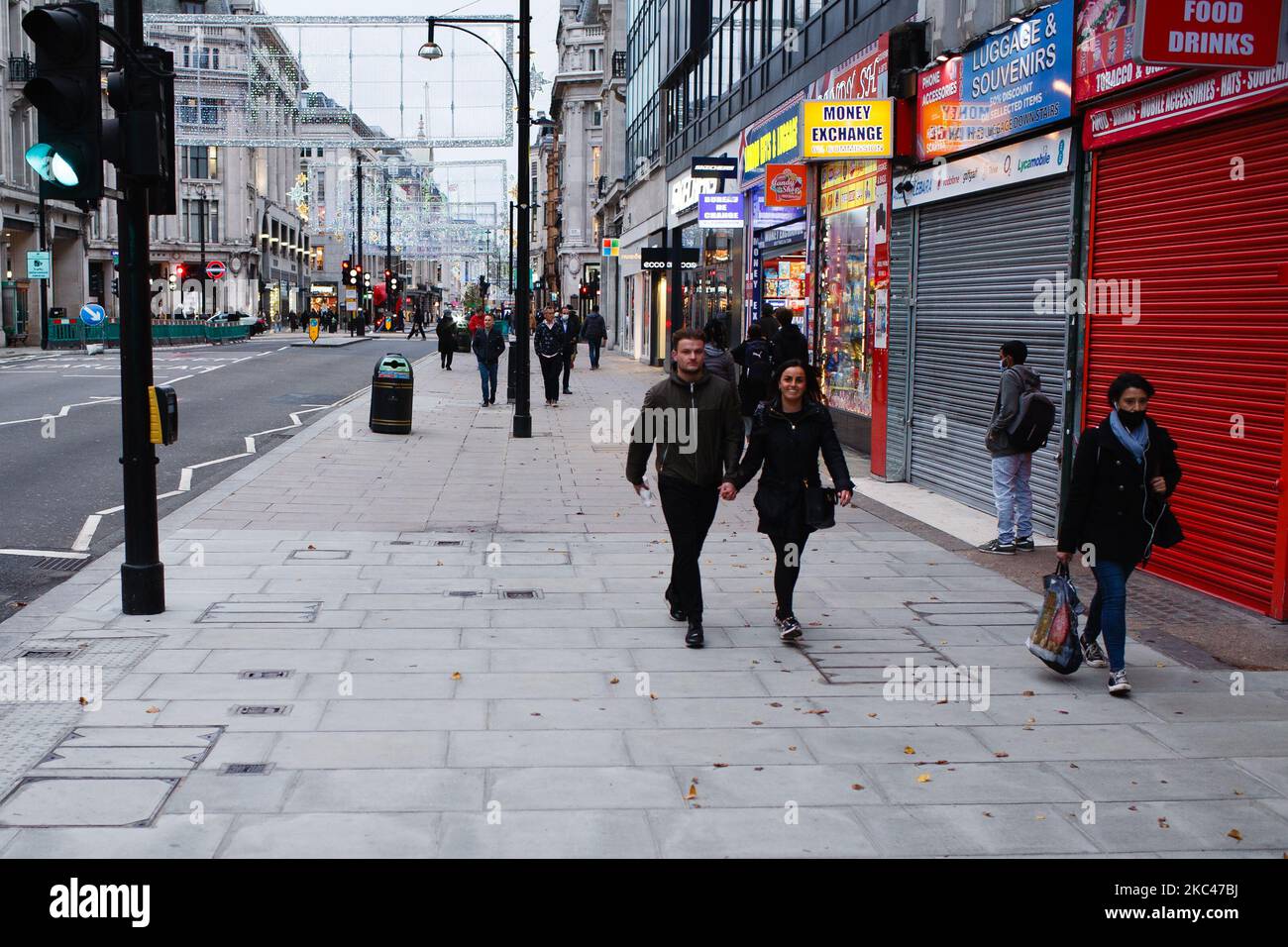 Il 18 novembre 2020, la gente passa accanto ai negozi di souvenir temporaneamente chiusi e chiusi in una tranquilla Oxford Street a Londra, Inghilterra. In tutta l'Inghilterra negozi non essenziali, bar, ristoranti e altre aziende del settore alberghiero rimangono chiusi come parte del secondo blocco nazionale del coronavirus, iniziato il 5 novembre e in scadenza il 2 dicembre. Il primo ministro britannico Boris Johnson, che ha dichiarato di non voler estendere il blocco, nel frattempo rimane in isolamento a Downing Street dopo essere venuto in contatto con un deputato giovedì scorso che ha poi testato positiv Foto Stock
