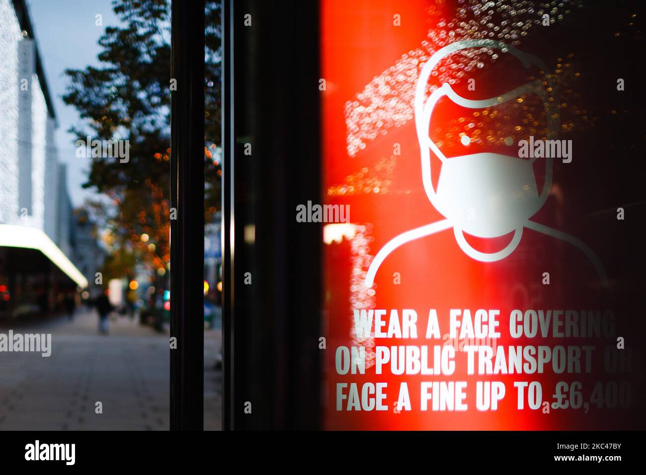Un cartello che ricorda agli utenti dei trasporti pubblici di indossare coperture facciali illumina lo schermo pubblicitario digitale di una fermata dell'autobus su una tranquilla Oxford Street a Londra, Inghilterra, il 18 novembre 2020. In tutta l'Inghilterra negozi non essenziali, bar, ristoranti e altre aziende del settore alberghiero rimangono chiusi come parte del secondo blocco nazionale del coronavirus, iniziato il 5 novembre e in scadenza il 2 dicembre. Il primo ministro britannico Boris Johnson, che ha dichiarato di non voler estendere il blocco, nel frattempo rimane in isolamento a Downing Street dopo essere venuto in contesa Foto Stock