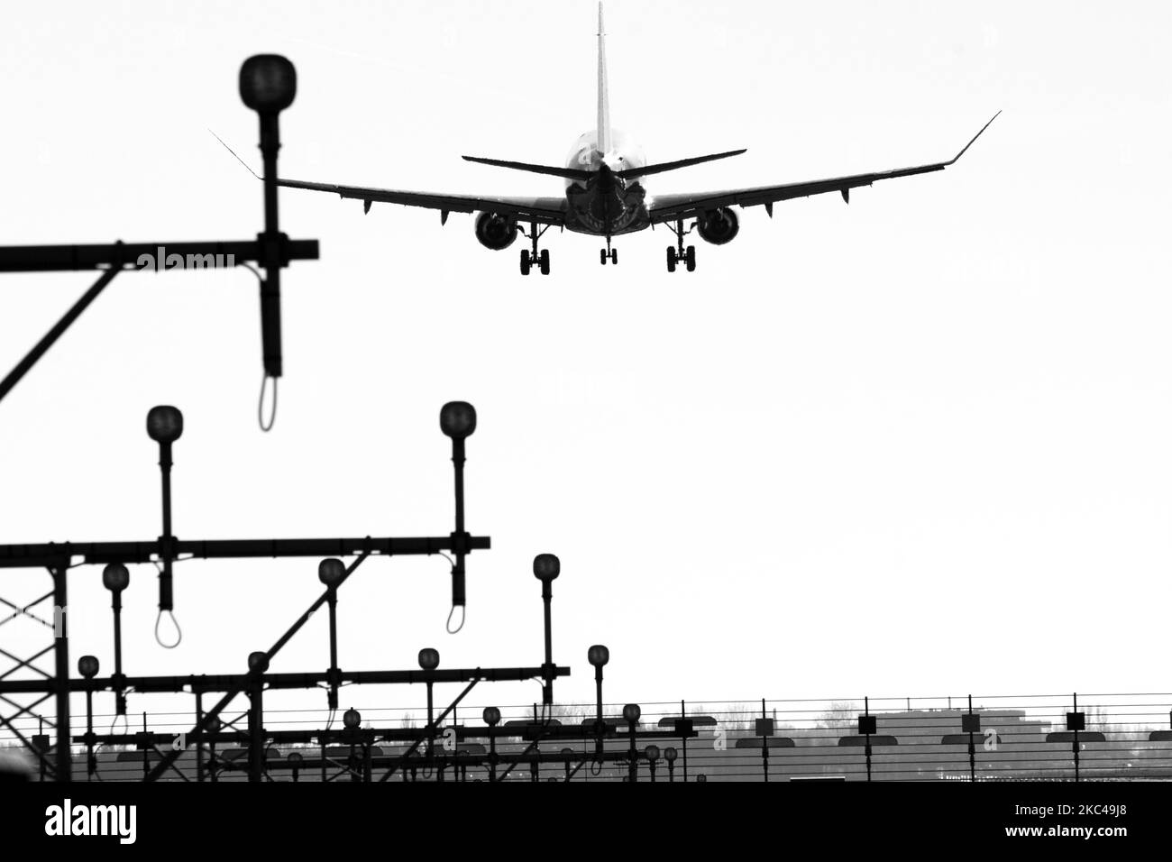 Foto in bianco e nero della vista posteriore di vari aerei che atterrano dietro le luci della pista di Amsterdam Schiphol AMS EHAM International Airport nei Paesi Bassi. Il traffico mondiale di passeggeri è diminuito durante l'era pandemica del coronavirus covid-19, con l'industria che lotta per sopravvivere. Amsterdam, Paesi Bassi il 18 novembre 2020 (Foto di Nicolas Economou/NurPhoto) Foto Stock