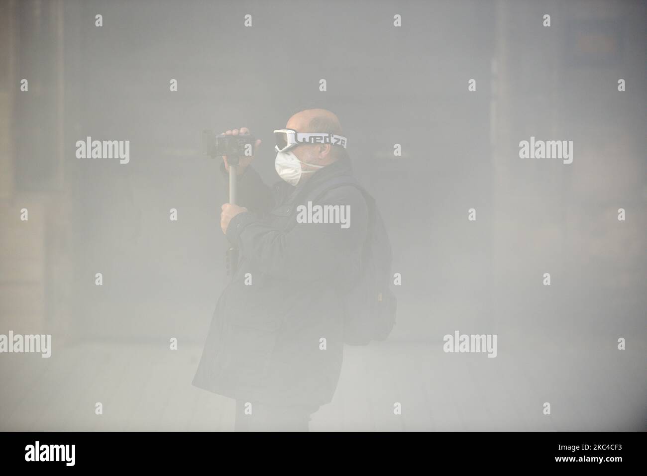 Un protester con una Handycam filma la polizia tra le nuvole di gas lacrimogeni. Se la 'Global Security Law' viene votata, sarà vietato filmare la polizia. Migliaia di manifestanti sono scesi in piazza dopo la chiamata delle ONG (Amnesty International, Human Rights League), dei sindacati (CGT, CNT, FO, SAF vale a dire Unione degli avvocati francesi), i sindacati dei giornalisti (SNJ, SNJ-CGT) e i partiti politici per una protesta contro la cosiddetta legge sulla sicurezza globale promossa dal presidente francese Macron e dalla sua maggioranza. Hanno anche chiesto più mezzi per gli ospedali come la 2nd onda di Covid-19 è qui. Alcuni giubbotti gialli anche c Foto Stock