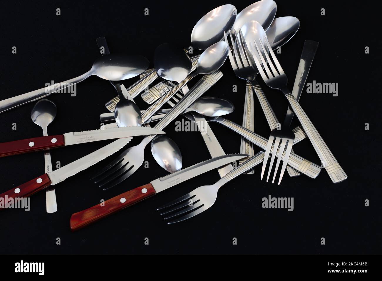 Forche, coltelli e cucchiai isolati su sfondo nero Foto Stock