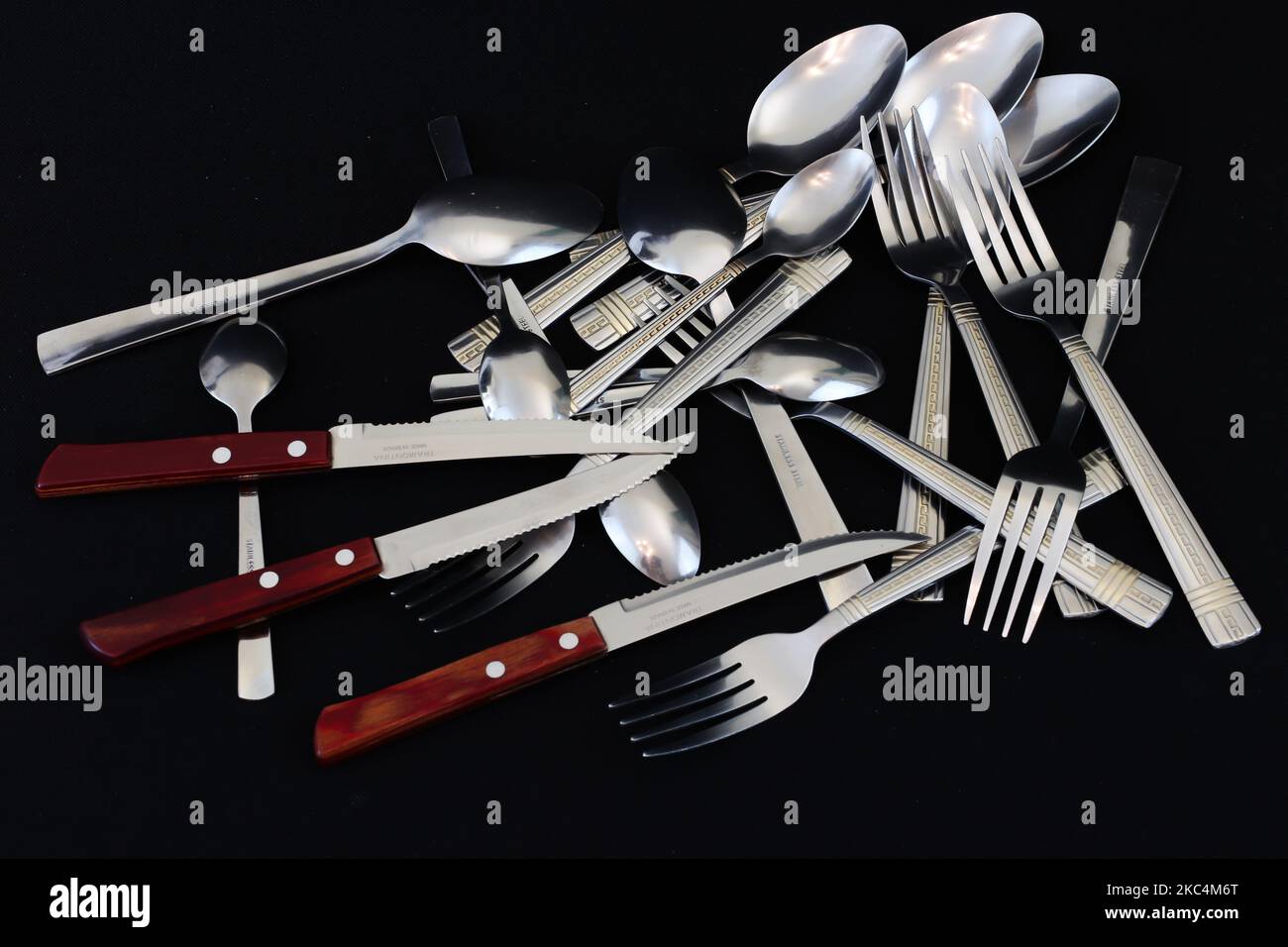 Forche, coltelli e cucchiai isolati su sfondo nero Foto Stock