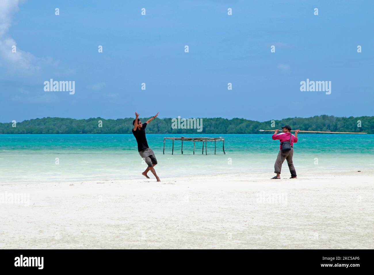 Due uomini giocano sulla spiaggia con sabbia bianca e mare turchese come sfondo. WiDi, Maluku settentrionale, Indonesia - 25 febbraio 2016 Foto Stock