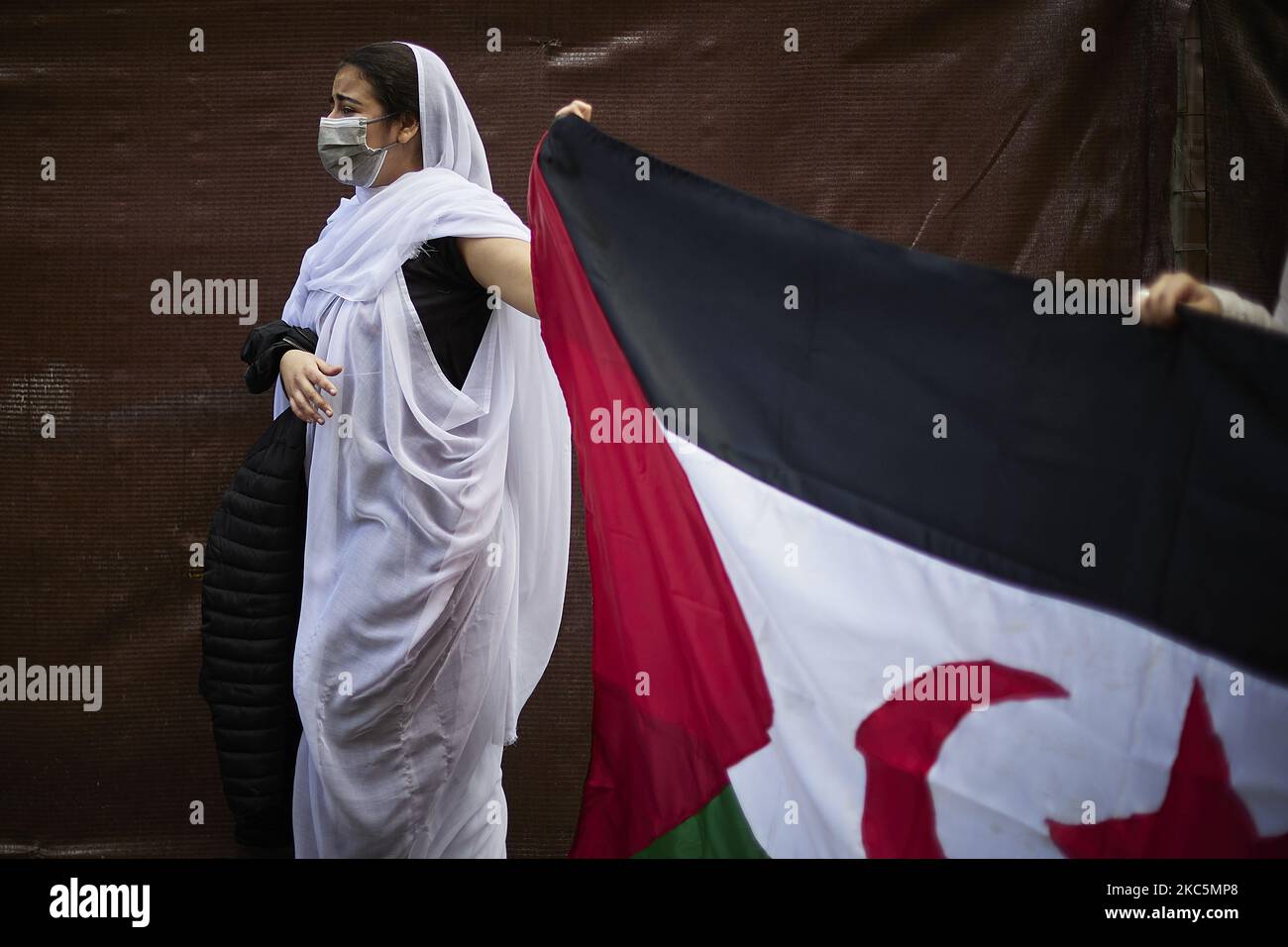 Una donna vestita in Malahfa porta una grande bandiera del Sahara durante una manifestazione a sostegno dei diritti del popolo saharawi a Granada il 12 dicembre 2020. Le città di tutta la Spagna si sono dimostrate favorevoli all'autodeterminazione nel Sahara occidentale e denunciano la violazione degli accordi di cessate il fuoco del 1991 la scorsa settimana. Ciò ha innescato la ripresa del conflitto armato tra l'esercito marocchino e il fronte Polisario. (Foto di Fermin Rodriguez/NurPhoto) Foto Stock