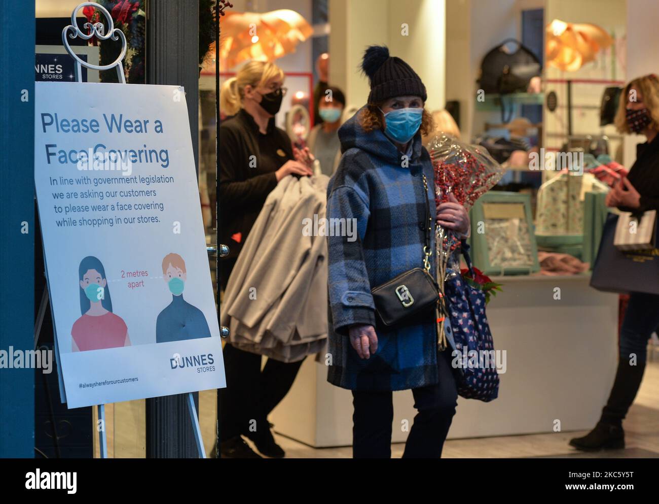 Una tavola con il messaggio "si prega di indossare una copertura facciale" visto all'ingresso dei negozi Dunnes nel centro di Dublino. Martedì 15 dicembre 2020 a Dublino, Irlanda. (Foto di Artur Widak/NurPhoto) Foto Stock