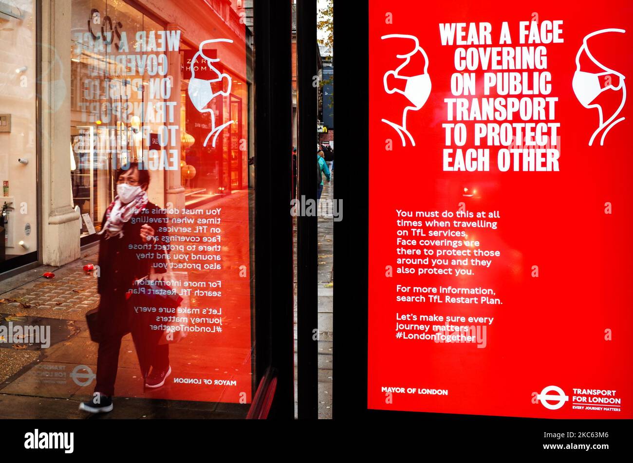 Una donna che indossa una maschera facciale passa davanti a un avviso che ricorda alle persone di indossare coperture facciali sui trasporti pubblici, visualizzato sullo schermo pubblicitario digitale di una fermata dell'autobus su Kensington High Street a Londra, Inghilterra, il 18 dicembre 2020. Le restrizioni di livello 3 sono iniziate a Londra il mercoledì tra le preoccupazioni delle autorità per l'aumento dei numeri covid-19 test positivi in città. I negozi possono rimanere aperti nelle aree di livello 3, ma le aziende del settore alberghiero sono limitate solo ai servizi di asporto e consegna e i luoghi di intrattenimento, inclusi teatri e cinema, devono essere chiusi. (Foto di David Cliff/NurPhoto) Foto Stock