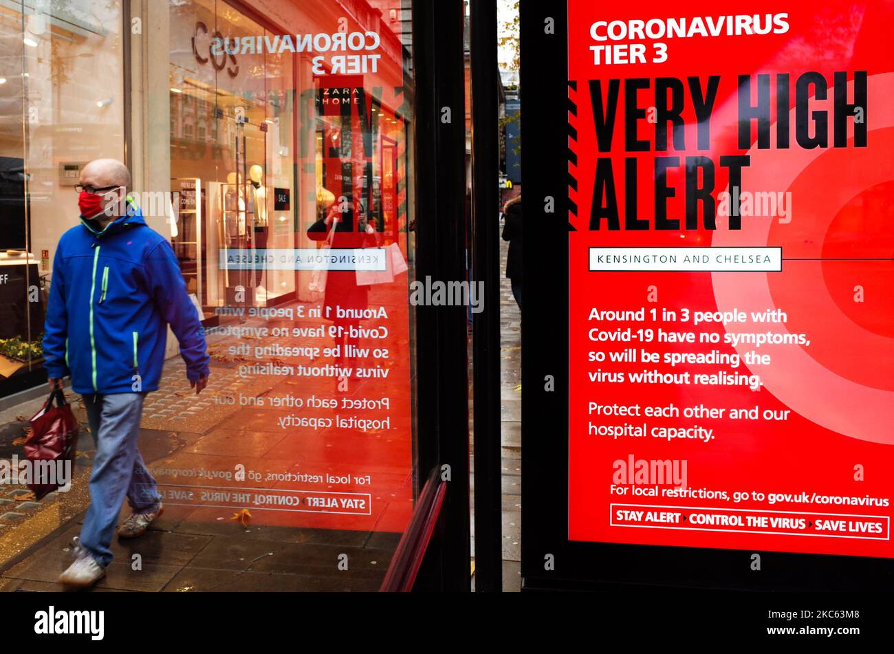 Un uomo che indossa una maschera facciale passa oltre un avviso per 'Tier 3' o 'molto alto' restrizioni di allarme coronavirus visualizzato sullo schermo di pubblicità digitale di una fermata di autobus su Kensington High Street a Londra, Inghilterra, il 18 dicembre 2020. Le restrizioni di livello 3 sono iniziate a Londra il mercoledì tra le preoccupazioni delle autorità per l'aumento dei numeri covid-19 test positivi in città. I negozi possono rimanere aperti nelle aree di livello 3, ma le aziende del settore alberghiero sono limitate solo ai servizi di asporto e consegna e i luoghi di intrattenimento, inclusi teatri e cinema, devono essere chiusi. (Foto di David Cliff/NurPhoto) Foto Stock