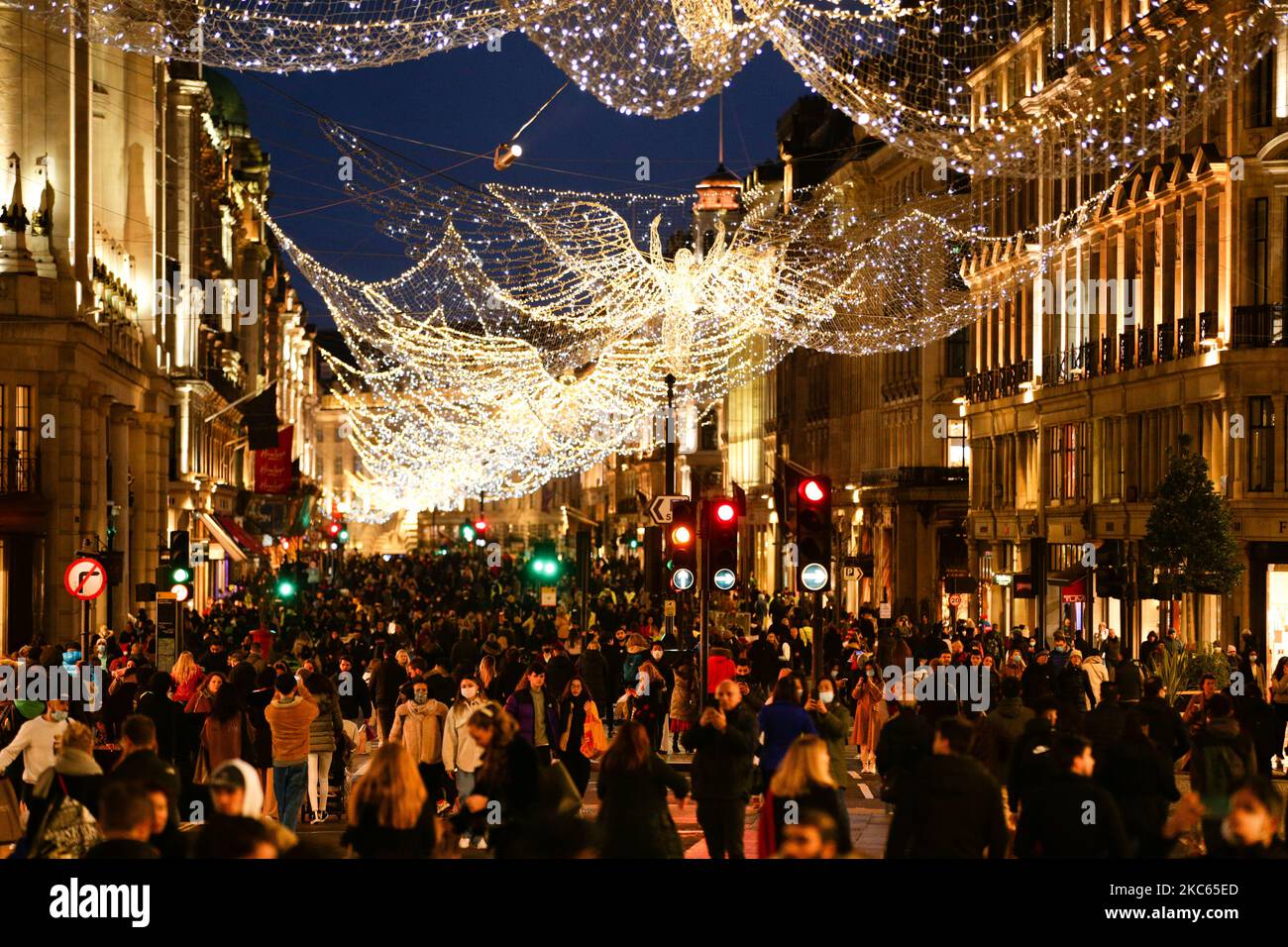 Gli acquirenti, alcuni indossano maschere facciali, camminano sotto le luci di Natale su una Regent Street temporaneamente pedonale a Londra, Inghilterra, il 19 dicembre 2020. Londra e gran parte del sud-est dell'Inghilterra saranno poste sotto una nuova 'Tier 4' di restrizioni sul coronavirus da mezzanotte stasera, il primo ministro britannico Boris Johnson ha annunciato questo pomeriggio, rispondere alle preoccupazioni delle autorità per la diffusione di un ceppo più infettivo del coronavirus che si ritiene stia facendo salire le ospedalizzazioni in queste parti del paese. In base alle regole del livello 4, i negozi non essenziali devono chiudere, come deve fare un haird Foto Stock