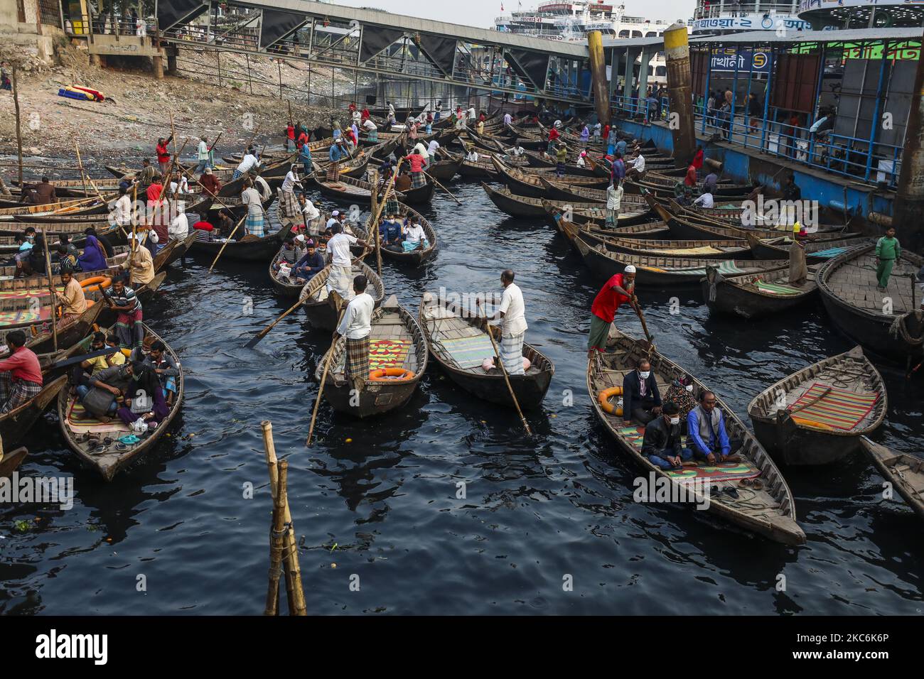 I barcaioli caricano i passeggeri sulle loro barche per portarli attraverso il fiume Buriganga al terminale di Sadarghat a Dhaka il 29 dicembre 2020. Il Buriganga è economicamente un fiume molto importante per la capitale. Lanci e barche collegano la capitale ad altre parti di questo paese fluviale attraverso il Buriganga. (Foto di Ahmed Salahuddin/NurPhoto) Foto Stock