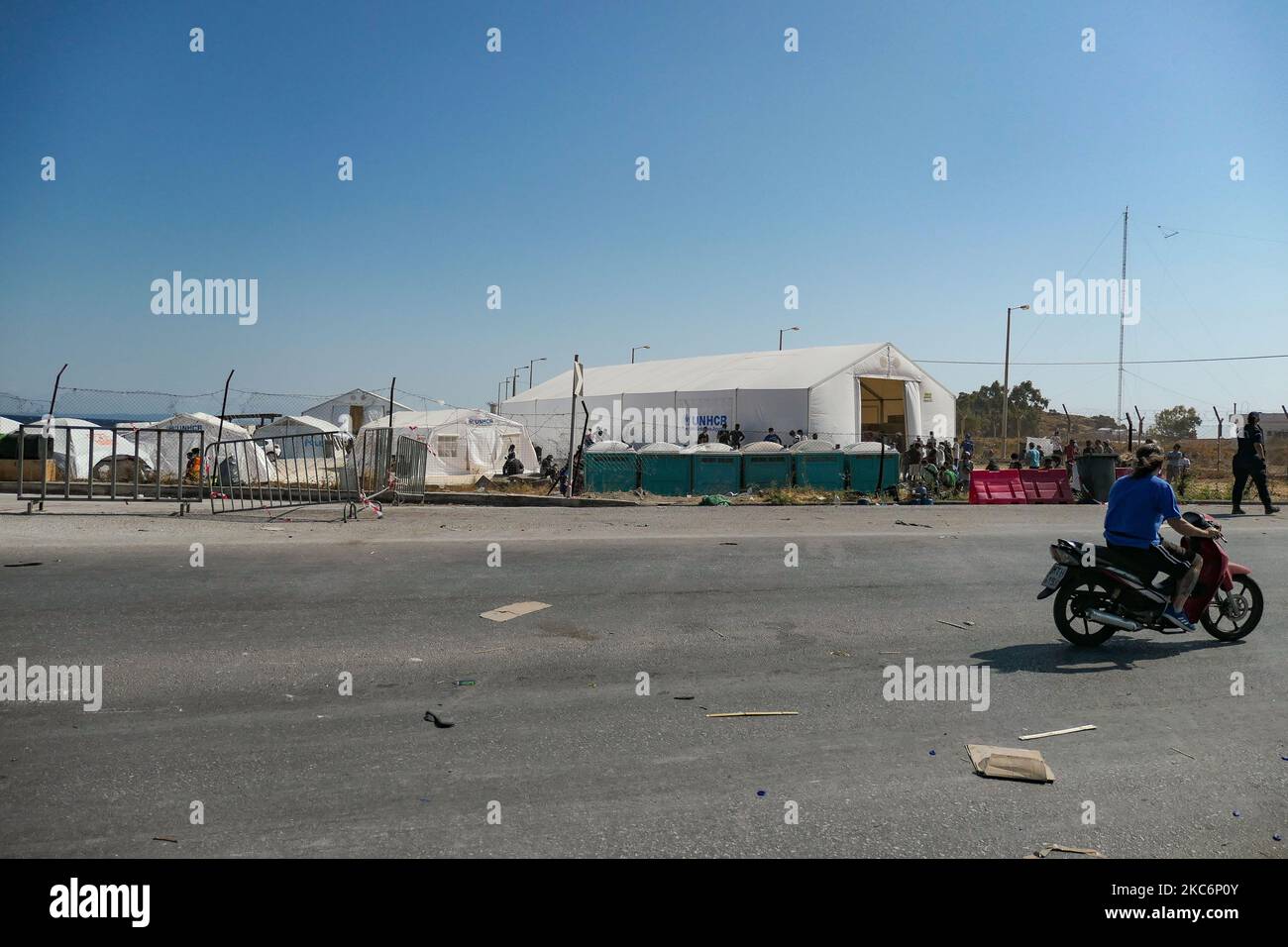 Nuovo campo temporaneo per rifugiati a Kara Tepe - Mavrovouni con grandi tende bianche con il logo UNHCR o UNICEF e richiedenti asilo in attesa di registrazione e forniture come cibo, letti, vestiti ecc come visto dall'ingresso principale custodito. Il nuovo campo recintato è un'ex area militare, campo di tiro dell'esercito ellenico, vicino alla città di Mytilene nell'isola di Lesbos Grecia. Il nuovo campo è stato creato dopo l'incendio del 9 settembre 2020, quando uno dei più grandi campi profughi d'Europa, il campo profughi di Moria (centro di accoglienza, identificazione e registrazione) è stato bruciato. Tutti i residenti, l'asilo cercano Foto Stock