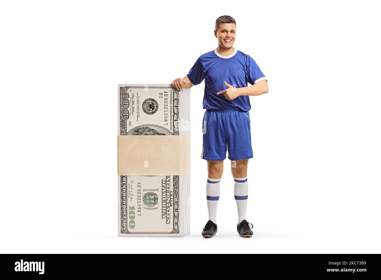 Uomo in una maglia sportiva che indica una pila di soldi isolato su sfondo bianco Foto Stock