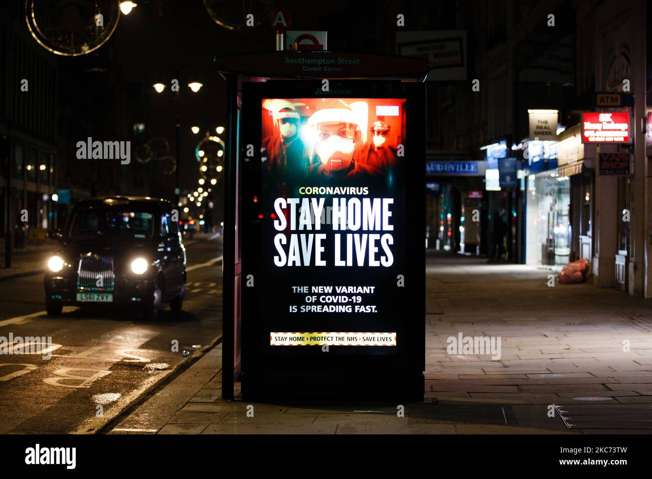 I messaggi del governo che dicono alle persone di rimanere a casa illuminano lo schermo della pubblicità digitale di una fermata dell'autobus su uno Strand vicino deserto a Londra, Inghilterra, il 7 gennaio 2021. All'inizio di questa settimana l'Inghilterra ha iniziato un terzo blocco nazionale del coronavirus, con la preoccupazione delle autorità di far sì che il Servizio sanitario Nazionale (NHS) possa presto essere sopraffatto dai malati di covid-19. Nel frattempo, il primo ministro britannico Boris Johnson ha annunciato oggi che 1,5m persone in tutto il Regno Unito hanno ricevuto almeno una prima dose di vaccino covid-19, con piani per centinaia di migliaia di vaccinazioni da somministrare ogni giorno Foto Stock