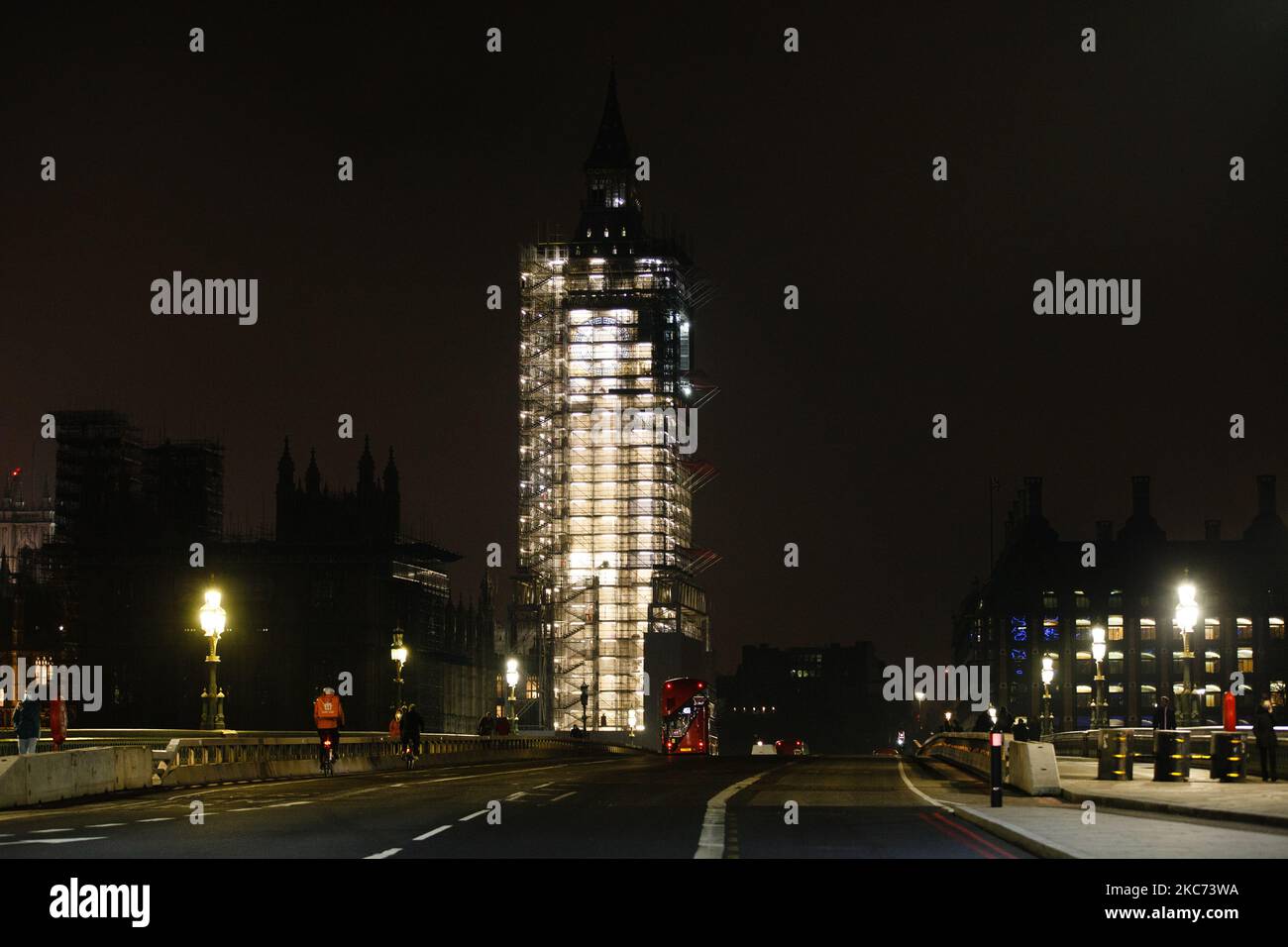 Un autobus attraversa un vicino ponte di Westminster a Londra, Inghilterra, il 7 gennaio 2021. All'inizio di questa settimana l'Inghilterra ha iniziato un terzo blocco nazionale del coronavirus, con la preoccupazione delle autorità di far sì che il Servizio sanitario Nazionale (NHS) possa presto essere sopraffatto dai malati di covid-19. Nel frattempo, il primo ministro britannico Boris Johnson ha annunciato oggi che 1,5m persone in tutto il Regno Unito hanno ricevuto almeno una prima dose di vaccino covid-19, con piani per centinaia di migliaia di vaccinazioni da somministrare ogni giorno a partire dalla metà di questo mese, con assistenza militare. (Foto di David Cliff/NurPhoto) Foto Stock