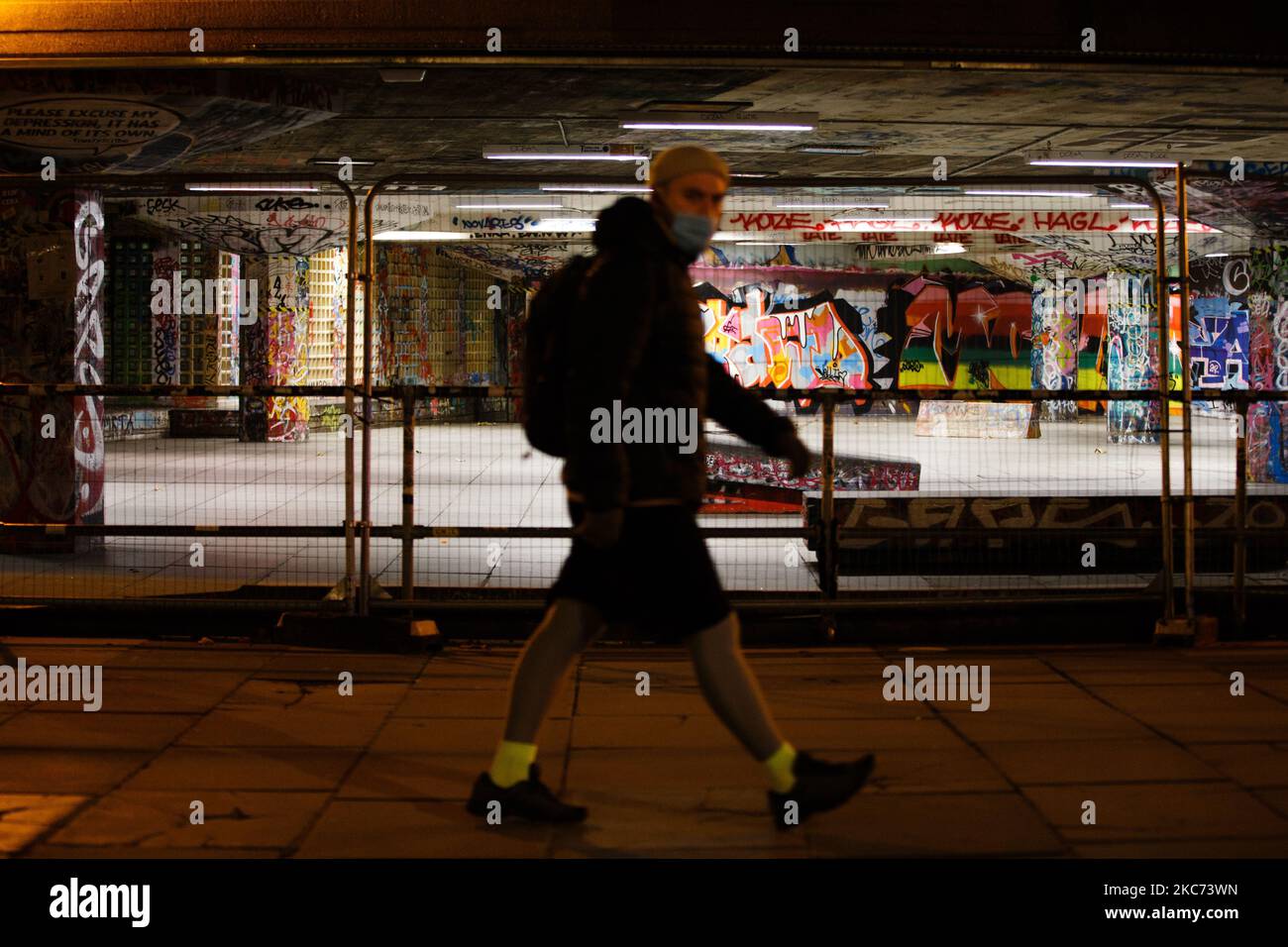 Un uomo che indossa una maschera facciale passa davanti a uno skate Park recintato su una South Bank quasi deserta a Londra, Inghilterra, il 7 gennaio 2021. All'inizio di questa settimana l'Inghilterra ha iniziato un terzo blocco nazionale del coronavirus, con la preoccupazione delle autorità di far sì che il Servizio sanitario Nazionale (NHS) possa presto essere sopraffatto dai malati di covid-19. Nel frattempo, il primo ministro britannico Boris Johnson ha annunciato oggi che 1,5m persone in tutto il Regno Unito hanno ricevuto almeno una prima dose di un vaccino covid-19, con piani per centinaia di migliaia di vaccinazioni da somministrare ogni giorno a partire dalla metà di questo mese, con una a militare Foto Stock