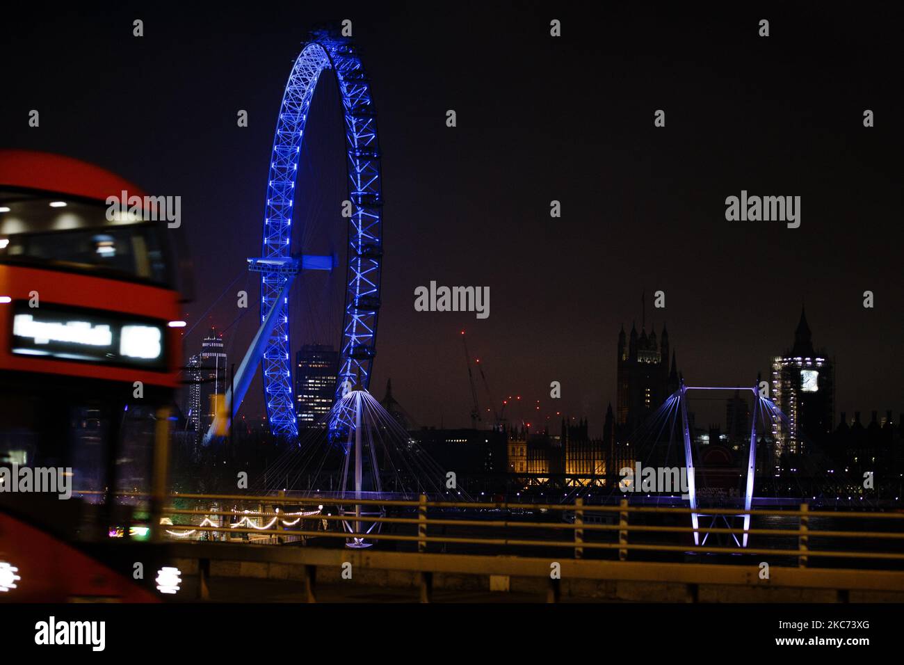 Un autobus attraversa Waterloo Bridge mentre il London Eye, illuminato di blu in onore del personale dell'NHS e di altri lavoratori frontline, si trova a Londra, Inghilterra, il 7 gennaio 2021. All'inizio di questa settimana, l'Inghilterra ha iniziato un terzo blocco nazionale del coronavirus, con la preoccupazione delle autorità di far sì che il Servizio sanitario nazionale possa presto essere sopraffatto dai malati di covid-19. Nel frattempo, il primo ministro britannico Boris Johnson ha annunciato oggi che 1,5m persone in tutto il Regno Unito hanno ricevuto almeno una prima dose di vaccino covid-19, con piani per centinaia di migliaia di vaccinazioni da somministrare ogni giorno a partire dalla metà di questo mese Foto Stock
