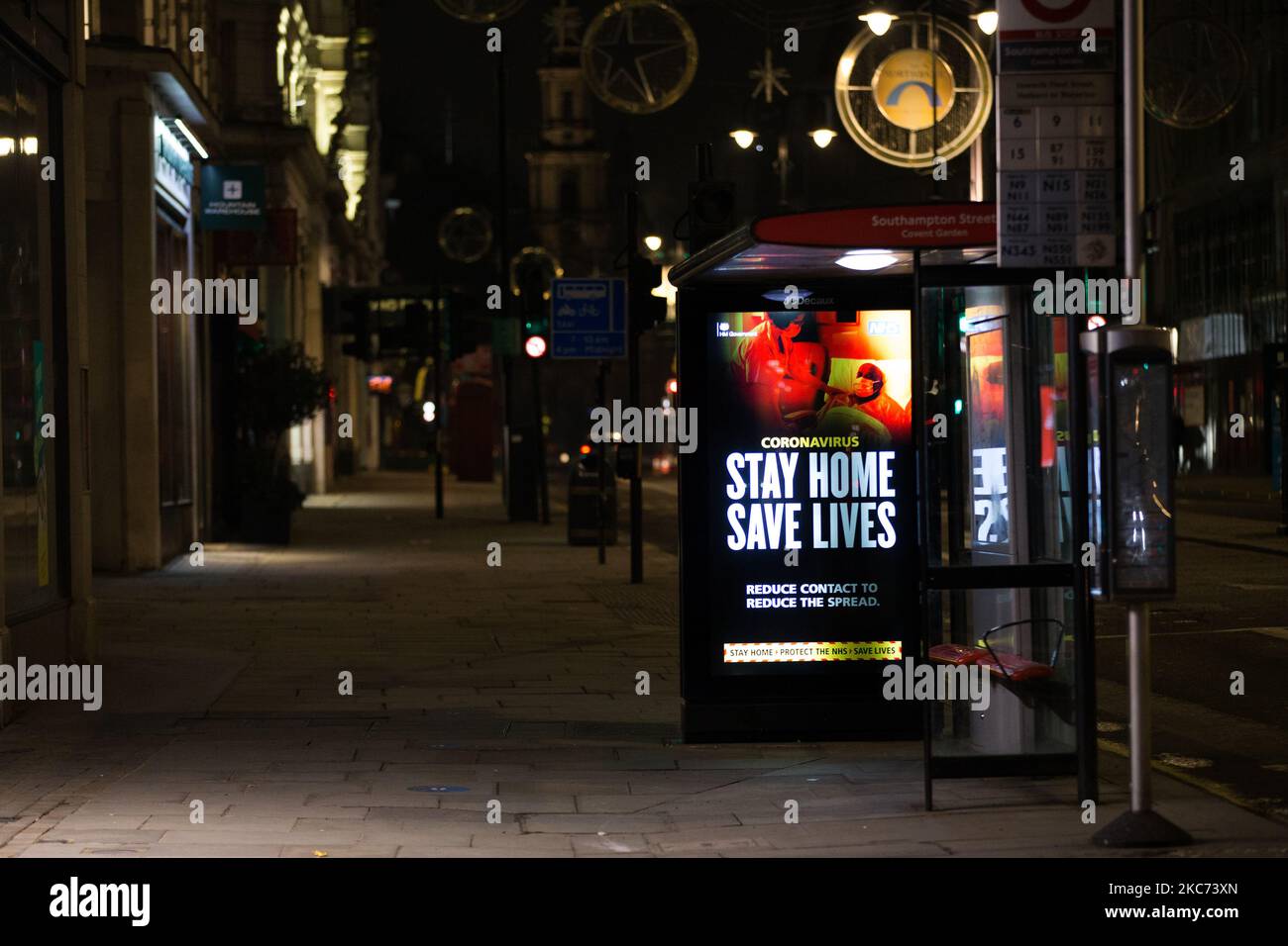 I messaggi del governo che dicono alle persone di rimanere a casa illuminano lo schermo della pubblicità digitale di una fermata dell'autobus su uno Strand vicino deserto a Londra, Inghilterra, il 7 gennaio 2021. All'inizio di questa settimana l'Inghilterra ha iniziato un terzo blocco nazionale del coronavirus, con la preoccupazione delle autorità di far sì che il Servizio sanitario Nazionale (NHS) possa presto essere sopraffatto dai malati di covid-19. Nel frattempo, il primo ministro britannico Boris Johnson ha annunciato oggi che 1,5m persone in tutto il Regno Unito hanno ricevuto almeno una prima dose di vaccino covid-19, con piani per centinaia di migliaia di vaccinazioni da somministrare ogni giorno Foto Stock