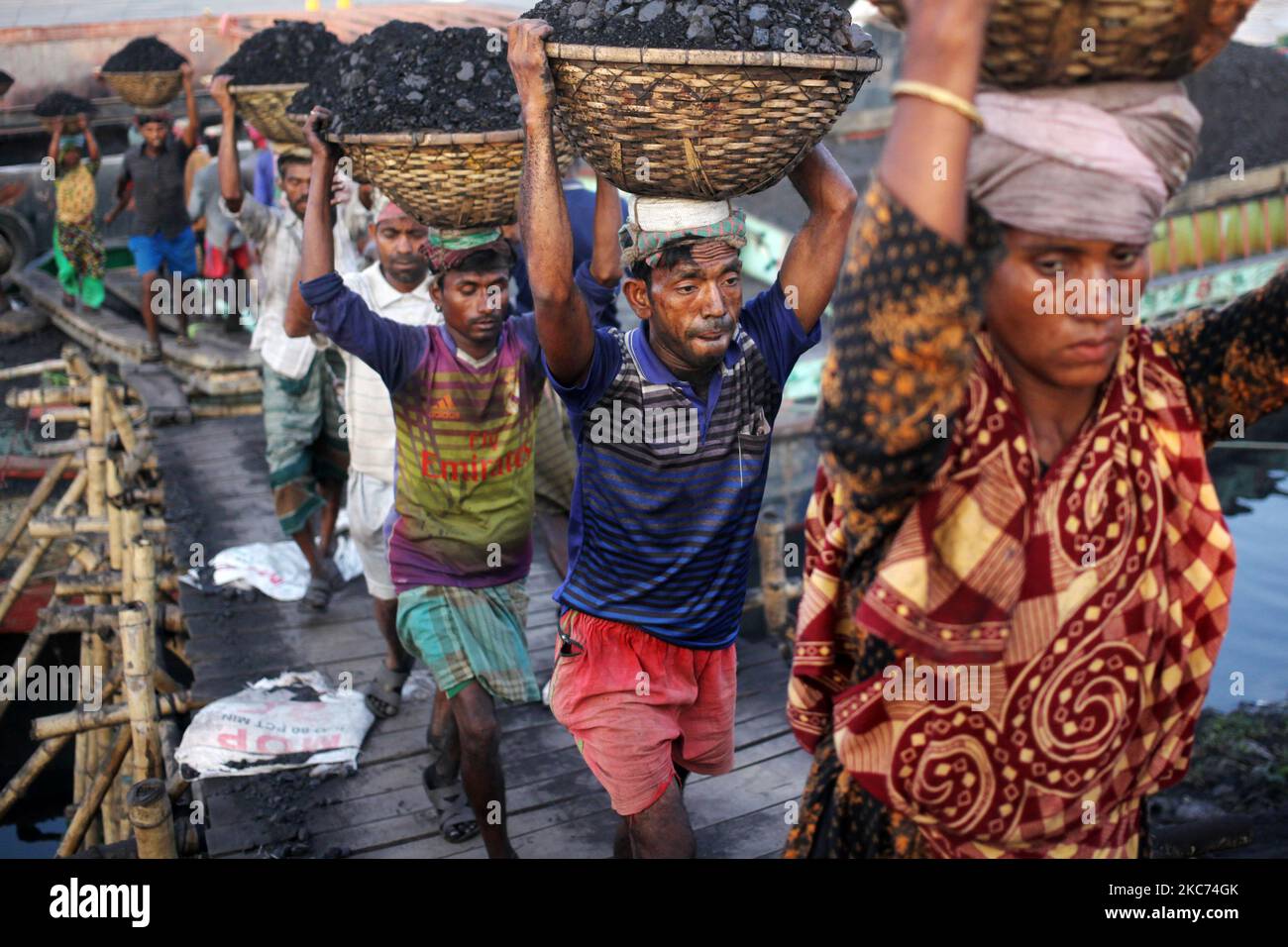 I lavoratori trasportano carbone sui cestini mentre scaricano questi da una nave di carico sulla riva del fiume Buriganga a Dhaka, Bangladesh venerdì 08 gennaio 2021. L'attuale consumo di carbone per la produzione di energia elettrica è di circa 3,5 milioni di tonnellate all'anno per le due centrali a carbone del Bangladesh, una a Barapukuria (440MW) a Dinajpur e l'altra è la centrale di Payra (660MW) di recente messa in servizio a Patuakhali. Secondo il rapporto dei media, se si attuasse il Master Plan 2016 del settore dell'energia, il consumo di carbone per la produzione di energia sarebbe 10 volte superiore nel 2030 e 20 volte superiore nel 2041 rispetto al pr Foto Stock