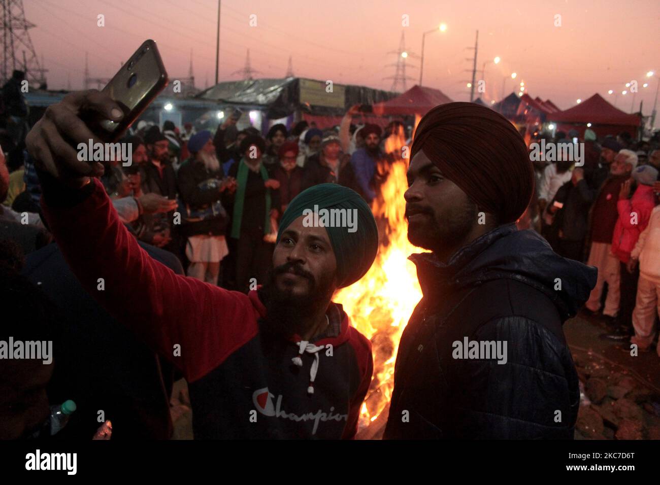 Gli agricoltori che protestano celebrano il festival di Lohri intorno a un falò, mentre bloccano una grande autostrada in protesta contro le nuove leggi agricole al confine di stato Delhi-Utttar Pradesh vicino Ghazipur alla periferia di Nuova Delhi, India il 13 gennaio 2021. Decine di migliaia di agricoltori protestano per 49 giorni presso i punti di ingresso principali della capitale nazionale. (Foto di Mayank Makhija/NurPhoto) Foto Stock