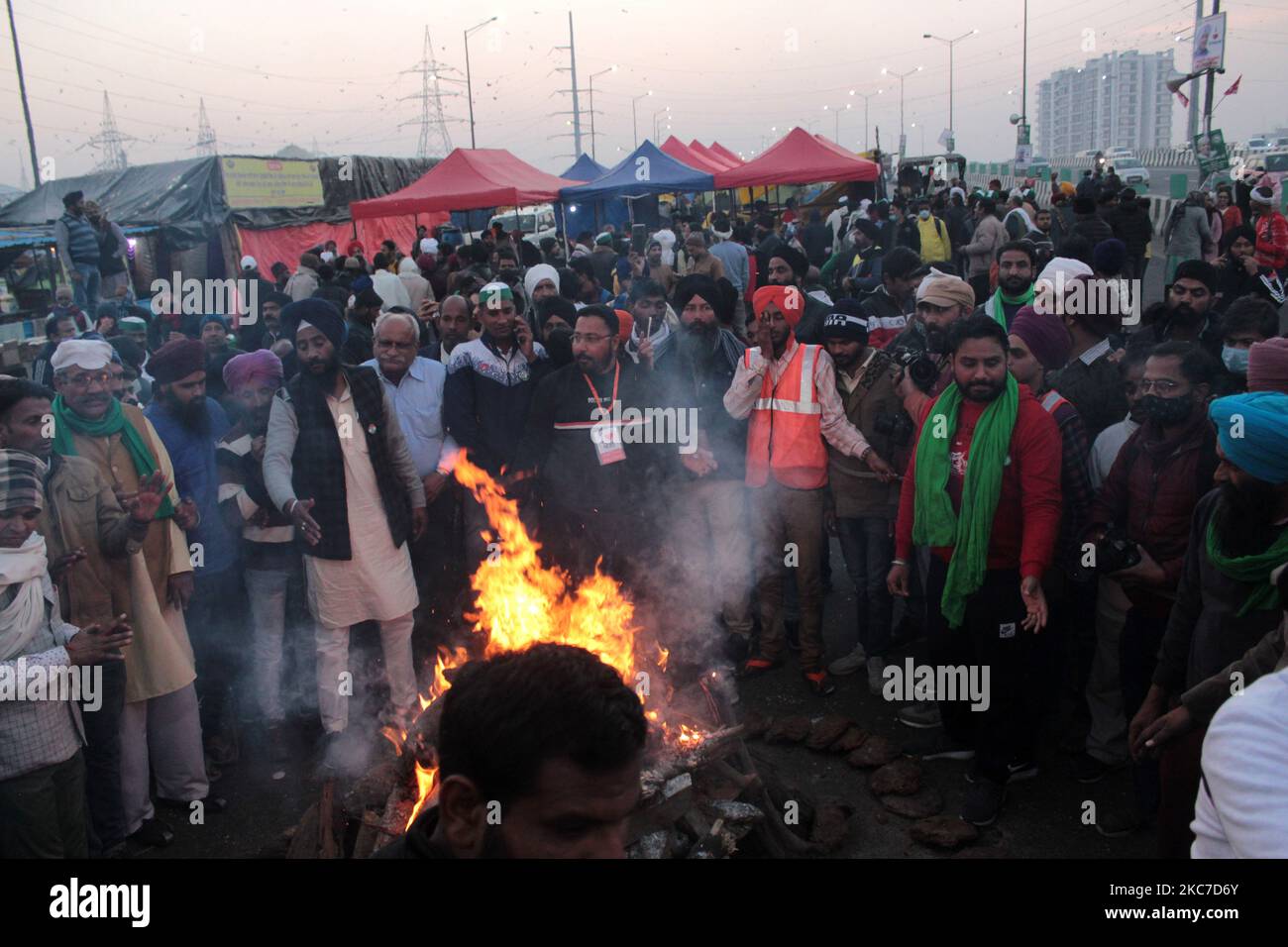 Gli agricoltori che protestano celebrano il festival di Lohri intorno a un falò, mentre bloccano una grande autostrada in protesta contro le nuove leggi agricole al confine di stato Delhi-Utttar Pradesh vicino Ghazipur alla periferia di Nuova Delhi, India il 13 gennaio 2021. Decine di migliaia di agricoltori protestano per 49 giorni presso i punti di ingresso principali della capitale nazionale. (Foto di Mayank Makhija/NurPhoto) Foto Stock