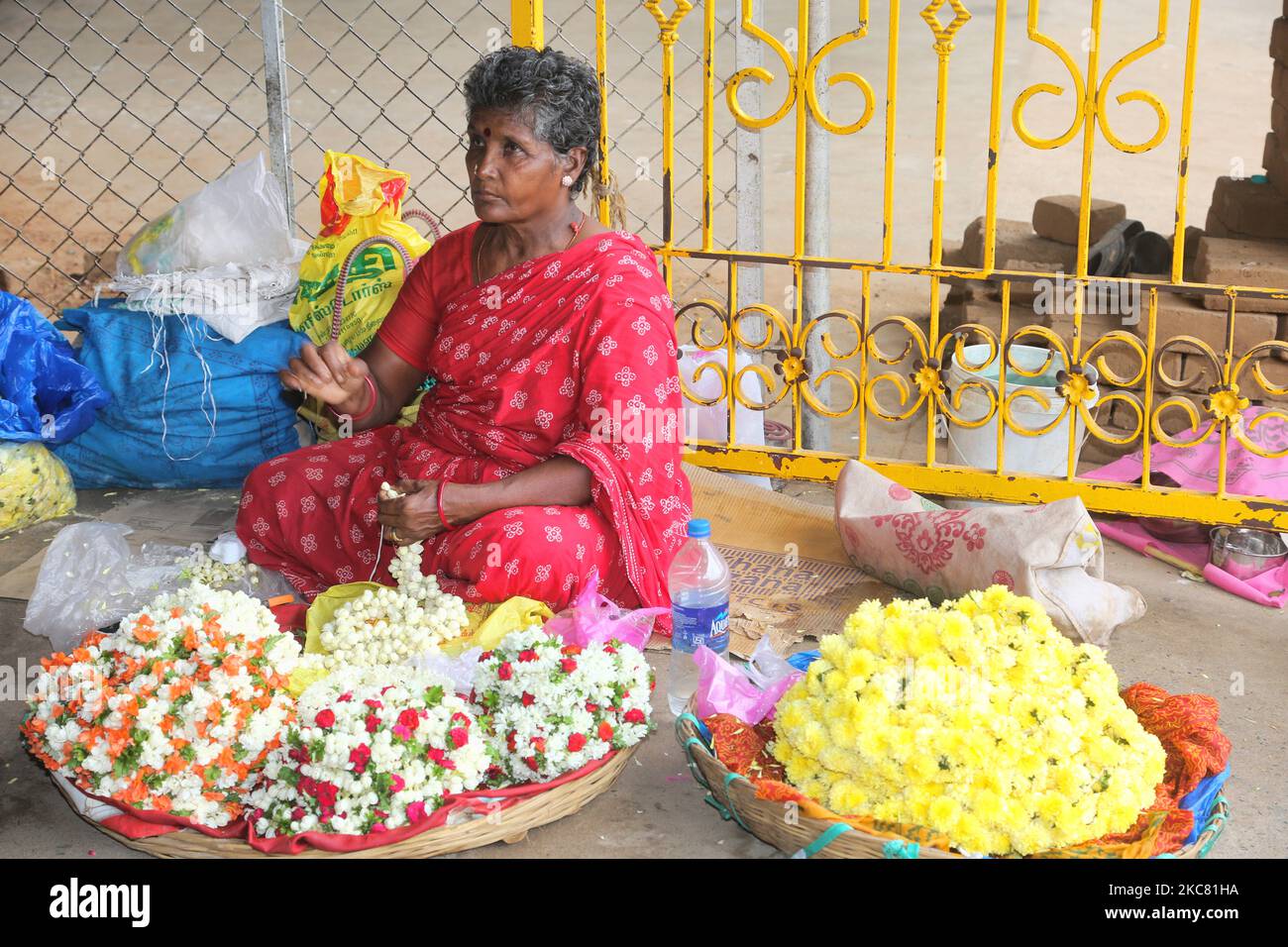 La donna vende fiori al Tempio di Amman di Melmaruvathur, situato a Melmaruvathur, Tamil Nadu, India. Arulmigu Adhiparasakthi Siddhar Peetam è il luogo dove 21 Siddhars (santi) uomini e donne di diverse religioni, hanno avuto loro Jeeva-Samadhis (cioè, dove i Siddhars hanno lasciato le loro forme umane dietro, mentre sono ancora vivi come spiriti santi). Qui in Melmaruvathur Adiparashakti Siddhar Peetam, la madre divina Adhi para sakthi trasmigrate in Arulthiru Bangaru Adigalar promuovendo così la spiritualità e la devozione. Arul Thiru Bangaru Adigalar è chiamato dai suoi devoti come AMMA (media Foto Stock