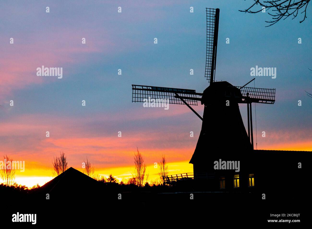 Un tradizionale mulino a vento olandese visto intorno all'ora del tramonto nel punto dolce chiamato ora magica al crepuscolo durante una fredda giornata invernale, dove il cielo chiaro e colorato si mescola con le nuvole. Il mulino a vento, un'attrazione turistica e simbolo del paese, si trova nella periferia di Veldhoven, vicino alla città di Eindhoven nella regione del Brabante Nord. Il mulino specifico è una panetteria e caffè, il Baker mulino Oerse. Veldhoven, Paesi Bassi il 25 gennaio 2021 (Foto di Nicolas Economou/NurPhoto) Foto Stock