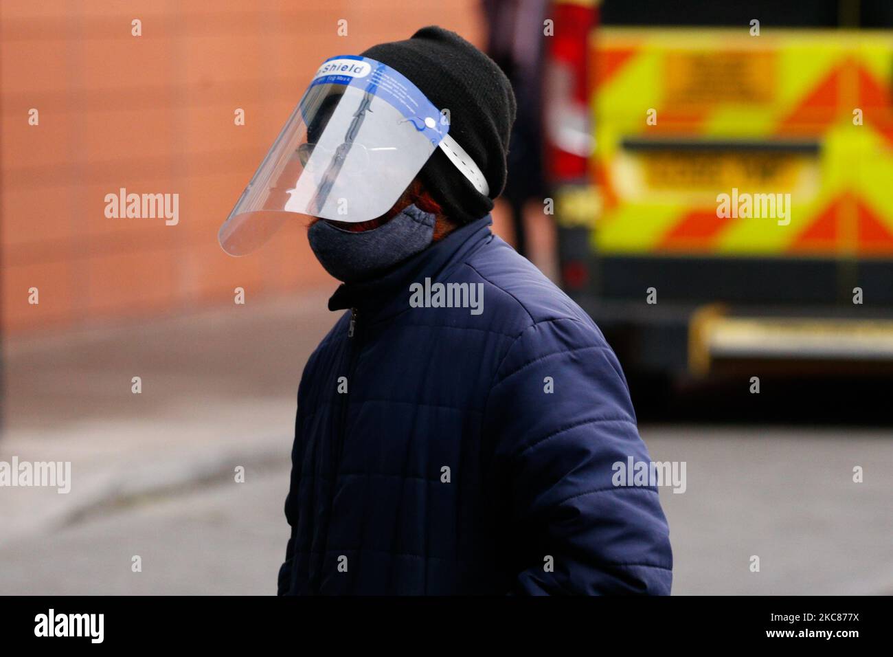Un membro del pubblico che indossa una maschera facciale e uno scudo facciale passa davanti alle ambulanze al di fuori del dipartimento di emergenza del Royal London Hospital di Londra, Inghilterra, il 26 gennaio 2021. I dati degli organismi ufficiali di statistica del Regno Unito hanno rivelato oggi che, sulla base dei certificati di morte, fino al 15 gennaio di quest'anno quasi 104.000 persone sono morte con coronavirus dall'inizio della pandemia. Le cifre del governo, che si basano su decessi entro 28 giorni da un test positivo di covid-19, rimangono leggermente inferiori, ieri in piedi a 98.531. (Foto di David Cliff/NurPhoto) Foto Stock