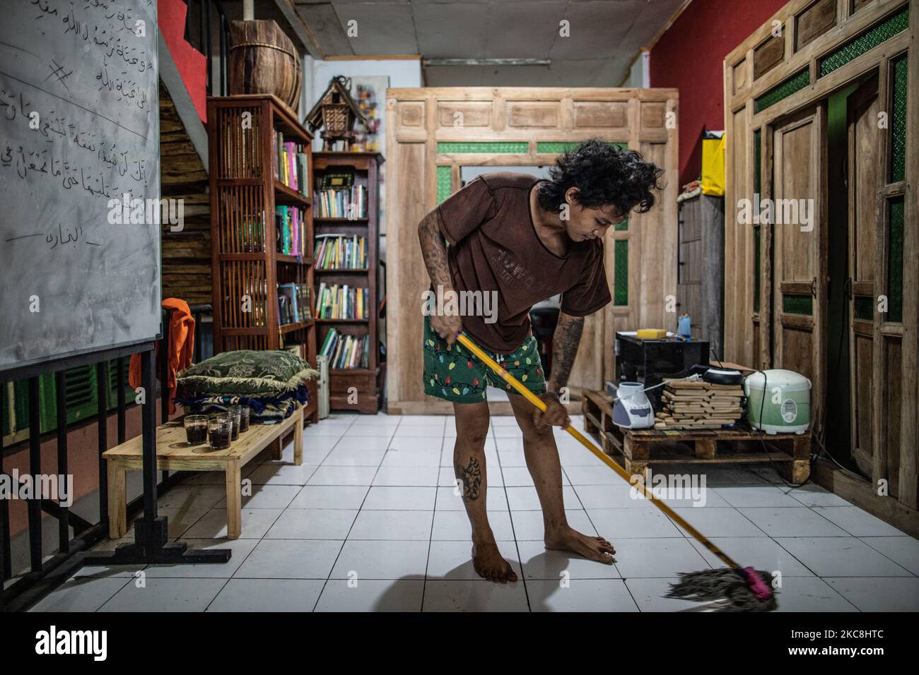 Un membro della scuola superiore pulisce il pavimento con tatuaggi al sopra del suo corpo. Scuola islamica per bambini punk e di strada a Ruko Cimanggis, Ciputat, South Tangerang, Banten, Indonesia, Il 1 febbraio 2021. Partendo da una storia di essere aiutato da bambini punk quando si va a attraversare da Thaliand in Malesia nella zona di Pattani, Ustadz HALIM AMBIYA ha poi aperto un pesantren per bambini punk e di strada che ha iniziato sotto il ponte nella zona di Tebet, a sud di Giacarta nel 2016, Con lo sviluppo dell'Ustadz Halim Ambiya, i bambini punk e di strada che volevano studiare l'Islam, poi si sono trasferiti a. Foto Stock