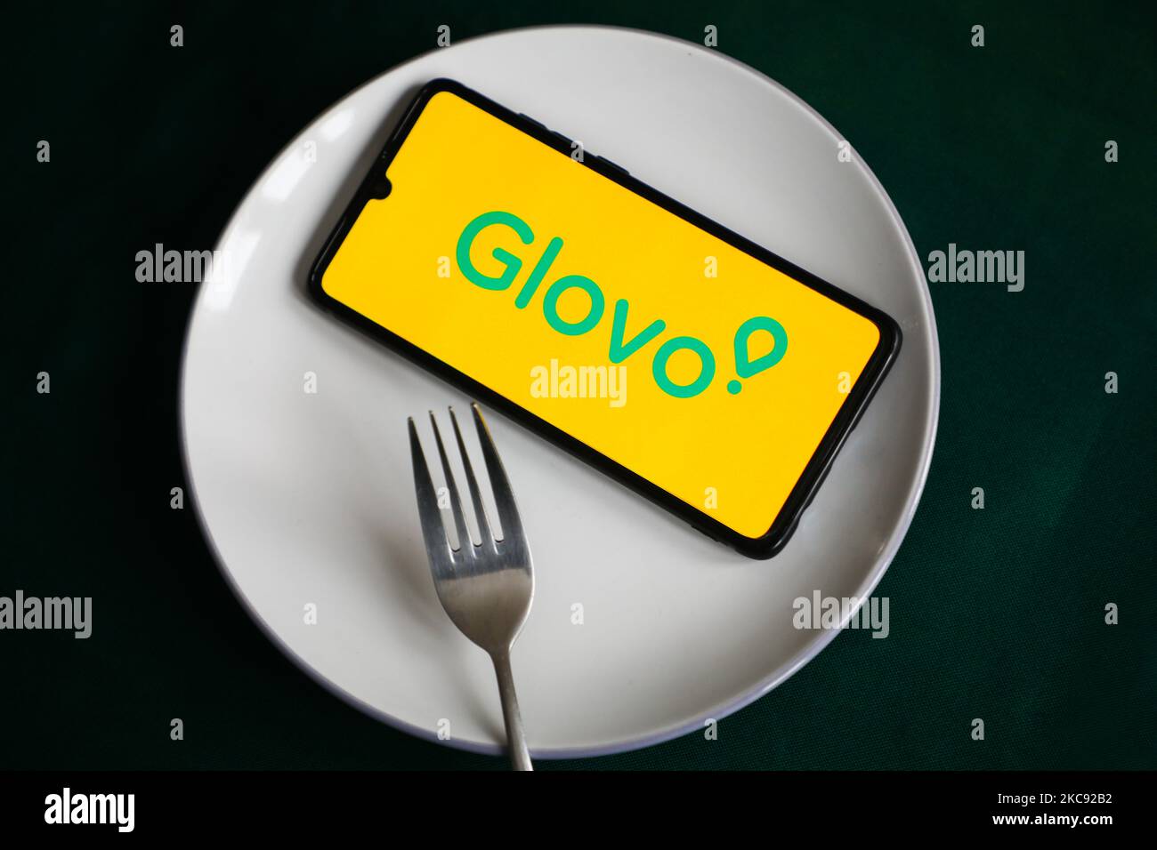 Il logo dell'app Glovo viene visualizzato sullo schermo di un telefono cellulare fotografato per l'illustrazione su un piatto e con posate. Cracovia, Polonia il 9 febbraio 2021. I numeri mostrano che la pandemia di Covid-19 ha determinato un aumento significativo dei pasti ordinati online attraverso le app e i siti web per la consegna dei prodotti alimentari. (Foto di Beata Zawrzel/NurPhoto) Foto Stock