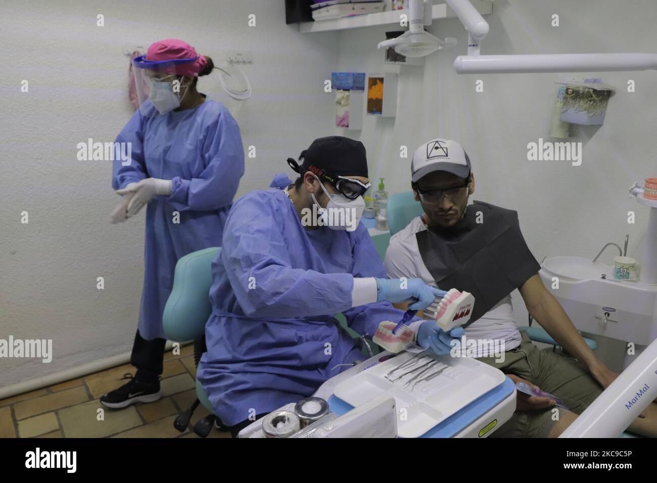 Ayax Malacate, chirurgo dentale, spiega la corretta spazzolatura di un paziente che ha assistito a una pulizia dentale durante l'emergenza sanitaria e un semaforo epidemiologico arancione, presso la sua clinica situata a Colonia Las Arboledas Tláhuac, Città del Messico. Prima dell'inizio della vaccinazione contro il COVID-19 in Messico, l'Unione dentale ha lanciato una campagna per rendere visibile la necessità di essere considerati nella prima fase del piano nazionale di vaccinazione, poiché nella loro pratica professionale quotidiana sono a rischio di essere infettati con coronavirus da essere in contatto diretto con la bocca e la saliva dei vostri pazienti. Th Foto Stock