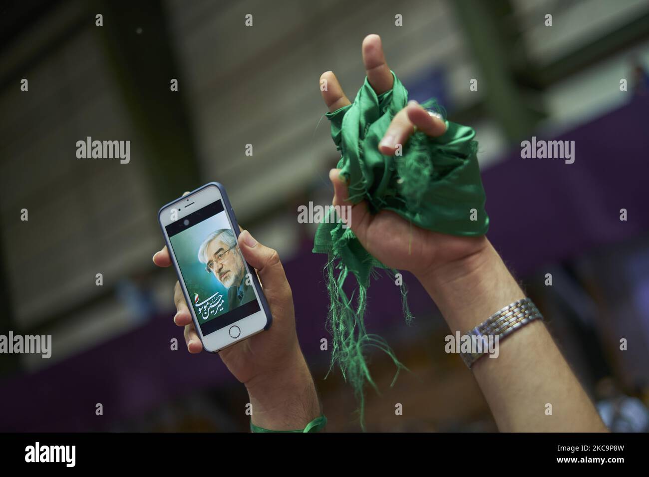 Un sostenitore del presidente riformista e del candidato alle elezioni presidenziali del 2017, Hassan Rouhani, tiene il suo smartphone come ritratto del leader iraniano dell'opposizione nei 2009 inarrestati post-elettorali, Mir-Hossein Mousavi è visto sul suo display e nastri verdi come lei frequenta il complesso sportivo Azadi (Freedom) 12000-sit durante un rally campagna nella parte occidentale di Teheran, 13 maggio 2017. Rouhani rieletto presidente dell'Iran. (Foto di Morteza Nikoubazl/NurPhoto) Foto Stock