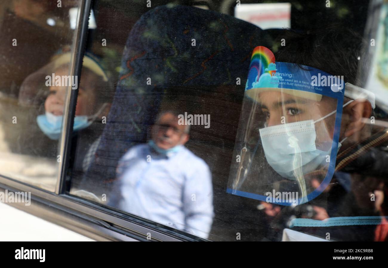 Un ragazzo palestinese, che indossa uno scudo facciale a causa della pandemia COVID-19, guarda fuori dalla finestra del suo autobus scolastico mentre i bambini sono riportati a casa a Gaza City il 22 febbraio 2021.- circa 20.000 dosi di vaccino contro il coronavirus dagli Emirati Arabi Uniti sono arrivate ieri a Gaza, Una consegna orchestrata da un rivale del presidente palestinese Mahmud Abbas tre mesi prima delle elezioni palestinesi programmate. (Foto di Majdi Fathi/NurPhoto) Foto Stock