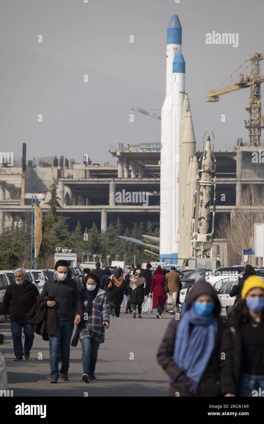 Le persone iraniane che indossano maschere protettive passeranno davanti ai missili da superficie a superficie iraniani e a due vettori satellitari mentre arriveranno per visitare il Parvaneh Friday-Bazaar (mercato) a Teheran centrale in mezzo alla nuova epidemia di coronavirus (COVID-19) in Iran, il 26 febbraio 2021. I funzionari iraniani hanno avvertito le persone che il paese è sull'orlo della quarta ondata dell'epidemia di COVID-19 e accadrà se le persone non manterranno protocolli sanitari, distensione sociale e smetteranno di viaggiare verso le altre città. (Foto di Morteza Nikoubazl/NurPhoto) Foto Stock