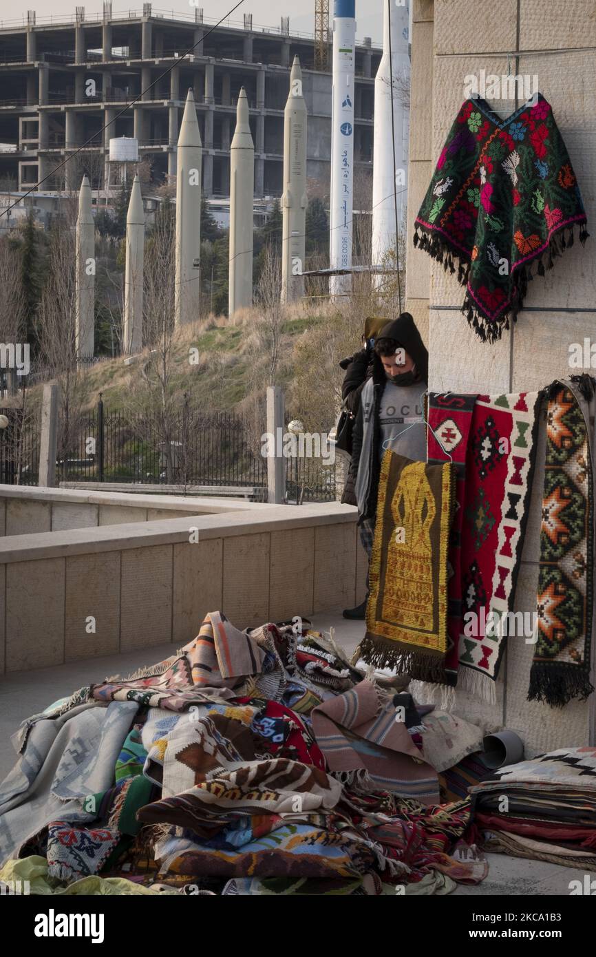 Un venditore iraniano si trova accanto ai suoi prodotti nel Parvaneh Friday-Bazaar (mercato), mentre missili iraniani superficie-superficie e due vettori satellitari sono visti sullo sfondo, nel centro di Teheran in mezzo alla nuova epidemia di coronavirus (COVID-19) in Iran, il 26 febbraio 2021. I funzionari iraniani hanno avvertito le persone che il paese è sull'orlo della quarta ondata dell'epidemia di COVID-19 e accadrà se le persone non manterranno protocolli sanitari, distensione sociale e smetteranno di viaggiare verso le altre città. (Foto di Morteza Nikoubazl/NurPhoto) Foto Stock