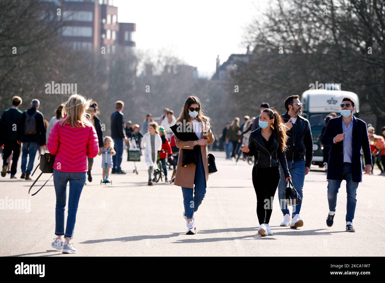 Le donne che indossano maschere facciali camminano attraverso il sole primaverile nei Kensington Gardens a Londra, Inghilterra, il 27 febbraio 2021. (Foto di David Cliff/NurPhoto) Foto Stock