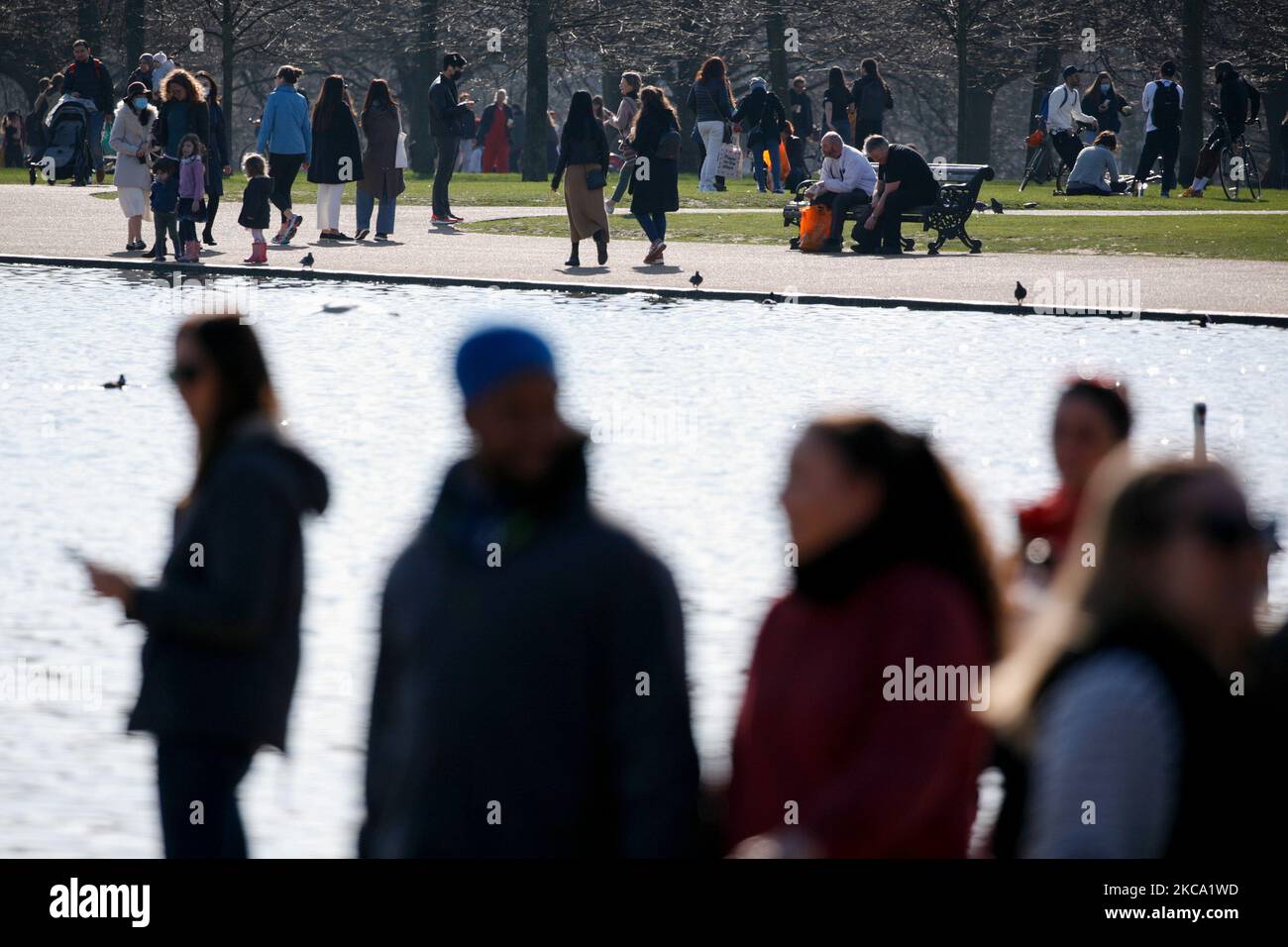La gente gode del sole primaverile accanto al Round Pond a Kensington Gardens a Londra, in Inghilterra, il 27 febbraio 2021. (Foto di David Cliff/NurPhoto) Foto Stock