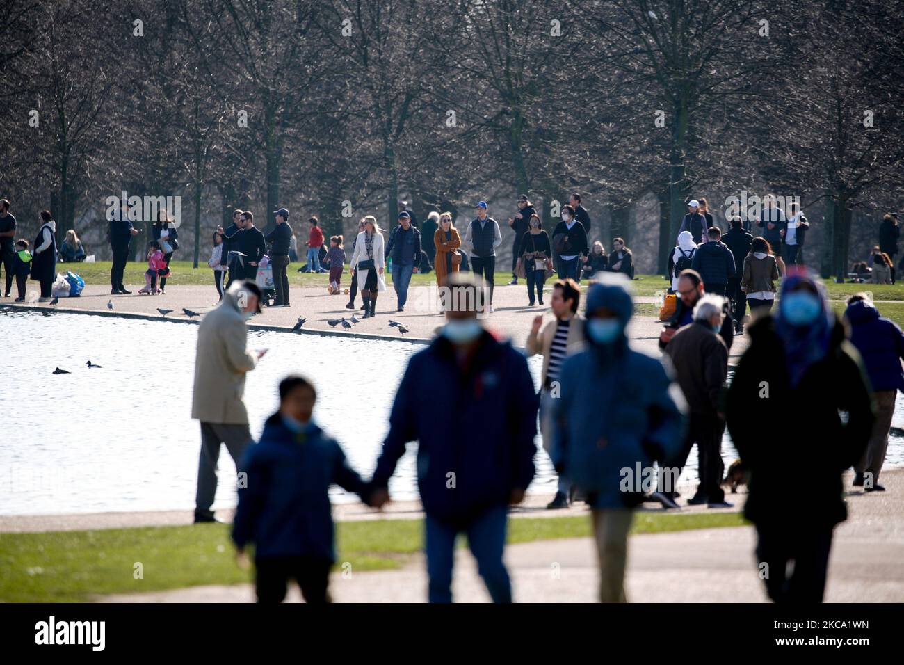 La gente gode del sole primaverile accanto al Round Pond a Kensington Gardens a Londra, in Inghilterra, il 27 febbraio 2021. (Foto di David Cliff/NurPhoto) Foto Stock