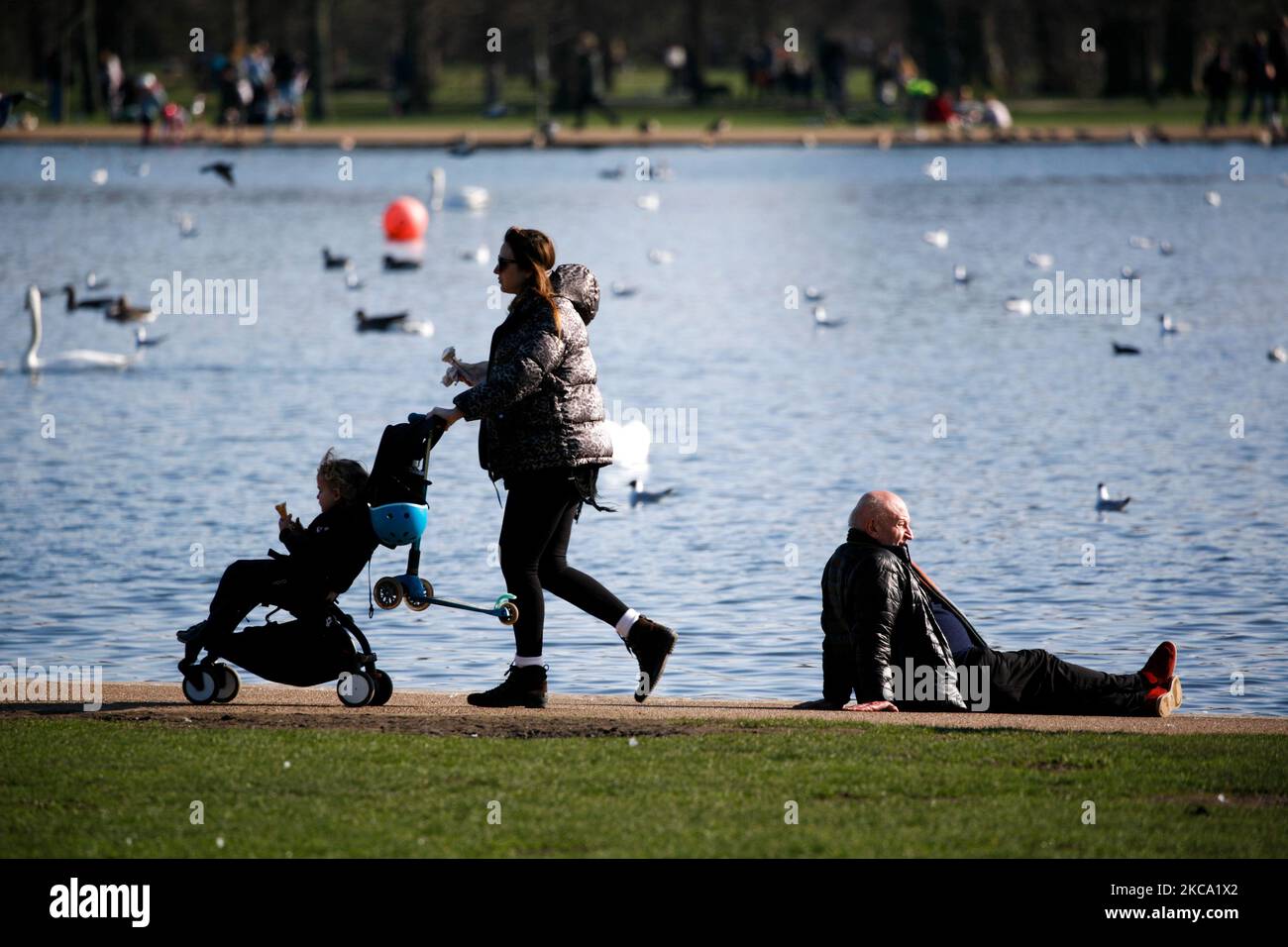 Un uomo si rilassa sotto il sole primaverile accanto al Round Pond a Kensington Gardens a Londra, Inghilterra, il 27 febbraio 2021. (Foto di David Cliff/NurPhoto) Foto Stock