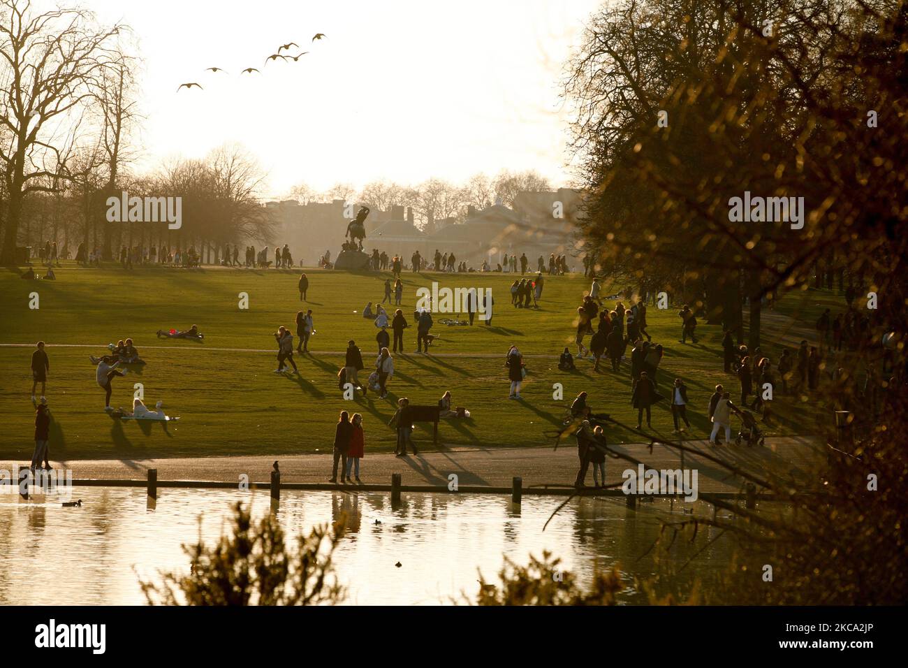 La gente cammina attraverso il sole primaverile nel tardo pomeriggio nei Kensington Gardens a Londra, Inghilterra, il 27 febbraio 2021. (Foto di David Cliff/NurPhoto) Foto Stock