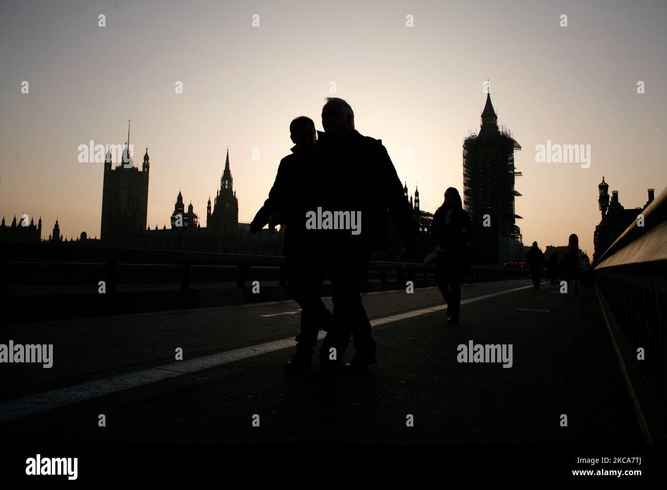 La gente attraversa il ponte di Westminster mentre il sole tramonta dietro le Camere del Parlamento a Londra, in Inghilterra, il 2 marzo 2021. (Foto di David Cliff/NurPhoto) Foto Stock