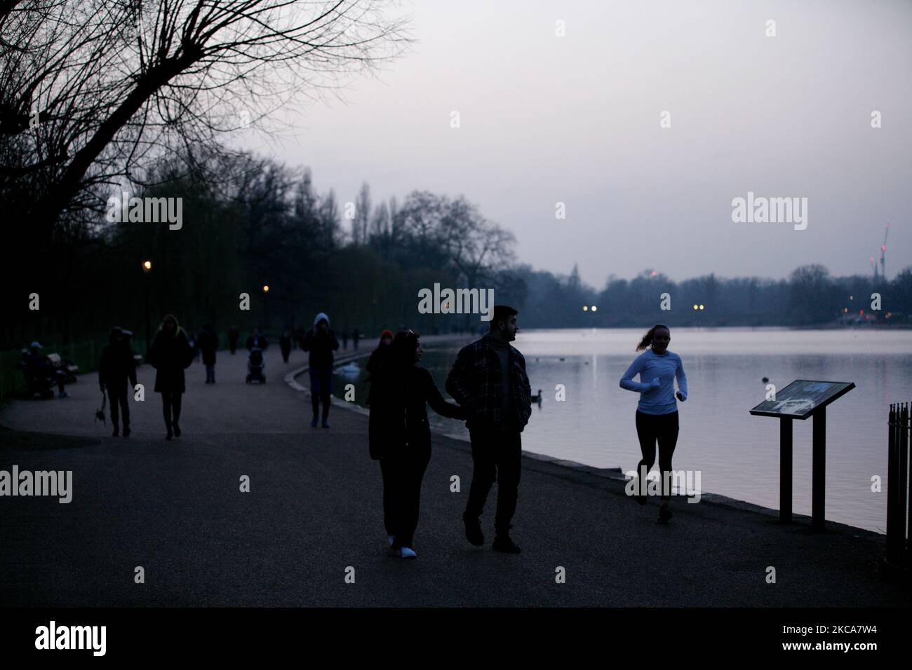 Una donna scherza accanto al lago serpentino di Hyde Park al tramonto a Londra, Inghilterra, il 2 marzo 2021. (Foto di David Cliff/NurPhoto) Foto Stock