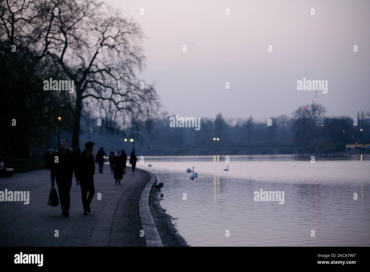 La gente cammina accanto al lago serpentino di Hyde Park al tramonto a Londra, Inghilterra, il 2 marzo 2021. (Foto di David Cliff/NurPhoto) Foto Stock