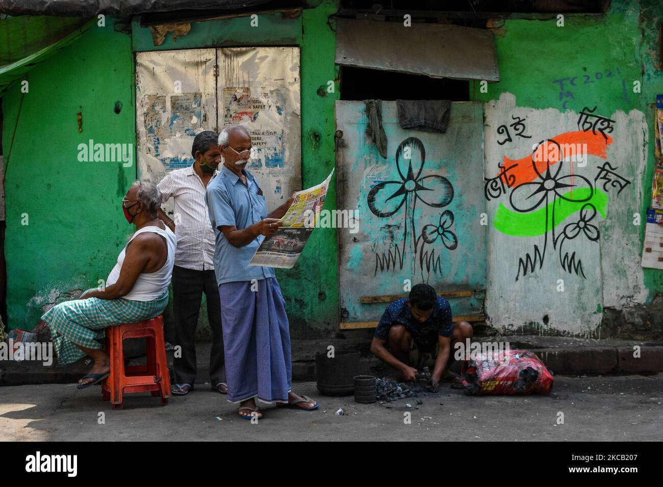 La gente è vista leggere il giornale ad un lato della strada con il manifesto della campagna politica del congresso DI CM Trinamool sulla parete di fondo a Kolkata , India , il 17 marzo 2021. (Foto di Debarchan Chatterjee/NurPhoto) Foto Stock