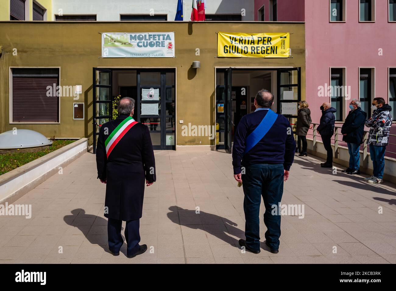 Il Sindaco di Molfetta Tommaso Minervini e il Presidente del Consiglio Comunale Nicola Piergiovanni, durante la giornata nazionale in memoria delle vittime del Coronavirus, osservano un minuto di silenzio di fronte alla bandiera italiana a mezza asta, presso il comune di Molfetta il 18 marzo 2021 a Molfetta, Italia. In seguito alla comunicazione del presidente di Anci Antonio Decaro a tutti i sindaci italiani di partecipare con un minuto di silenzio alla prima giornata nazionale in memoria delle vittime di Coronavirus. Alle 11 ha partecipato anche Molfetta, in concomitanza con l'arrivo a Bergamo del primo Ministro Foto Stock