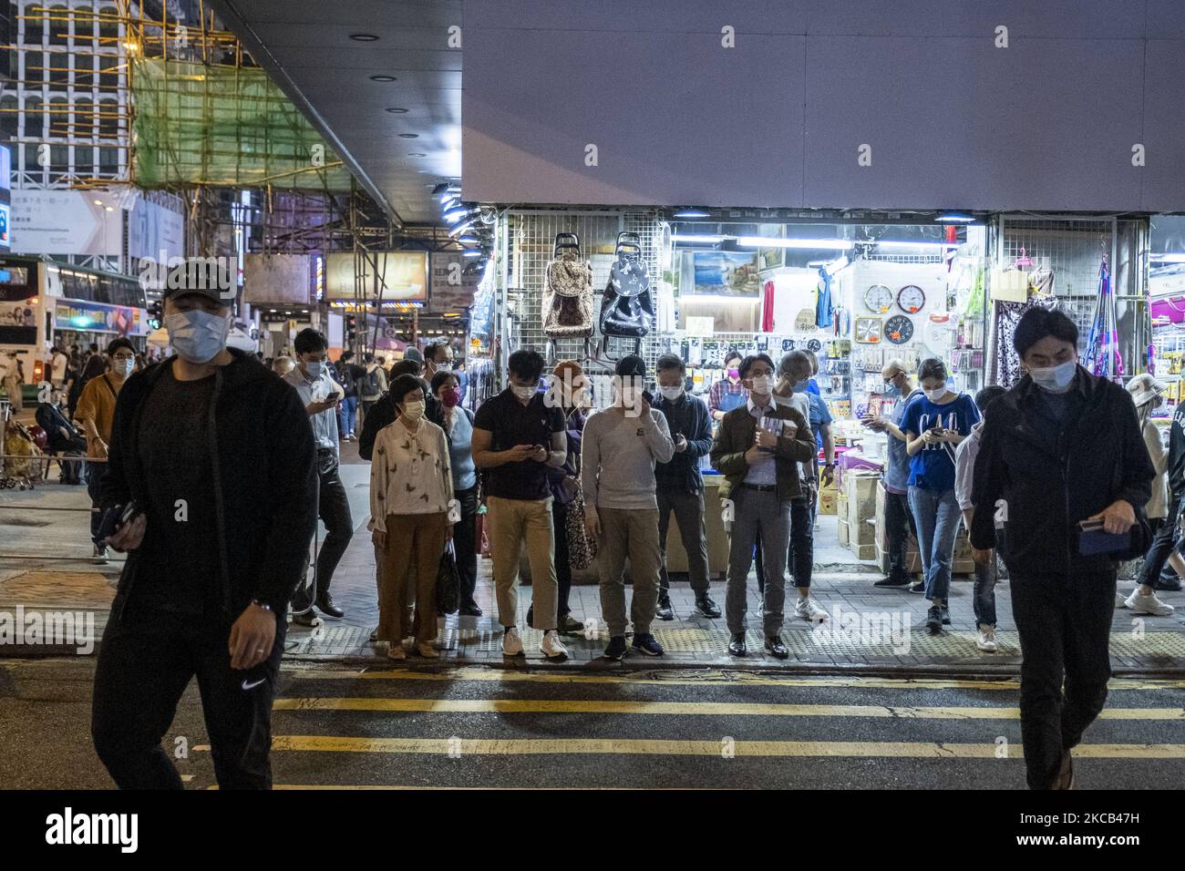 Le persone che indossano maschere facciali attraversano una strada a Hong Kong, giovedì 18 marzo 2021. (Foto di Vernon Yuen/NurPhoto) Foto Stock