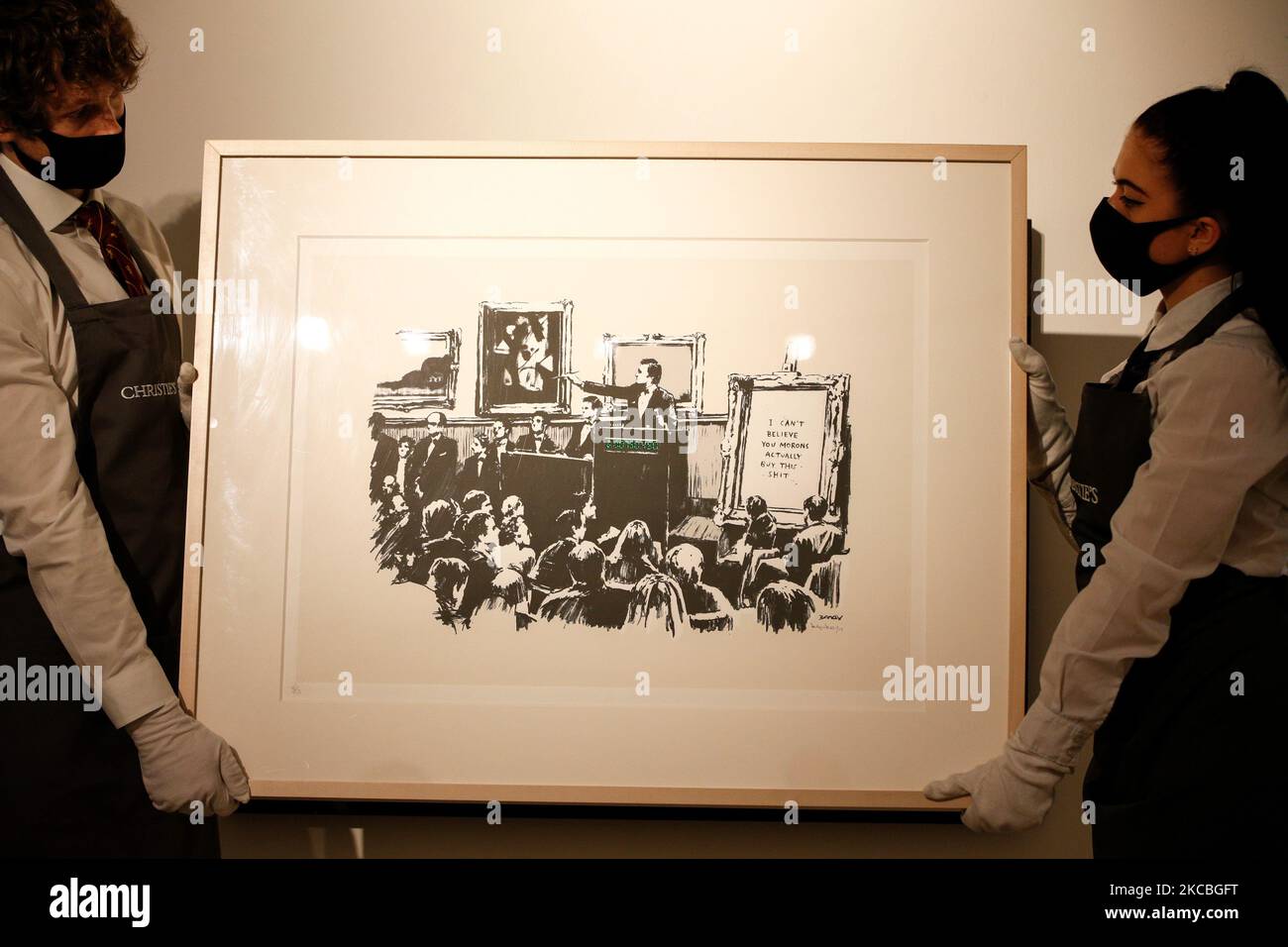 I gestori d'arte posano tenere 'morons (White)', dell'artista britannico Banksy, stimato a GBP40.000-60.000, durante un'anteprima alla casa d'aste di Christie a Londra, in Inghilterra, il 26 marzo 2021. (Foto di David Cliff/NurPhoto) Foto Stock