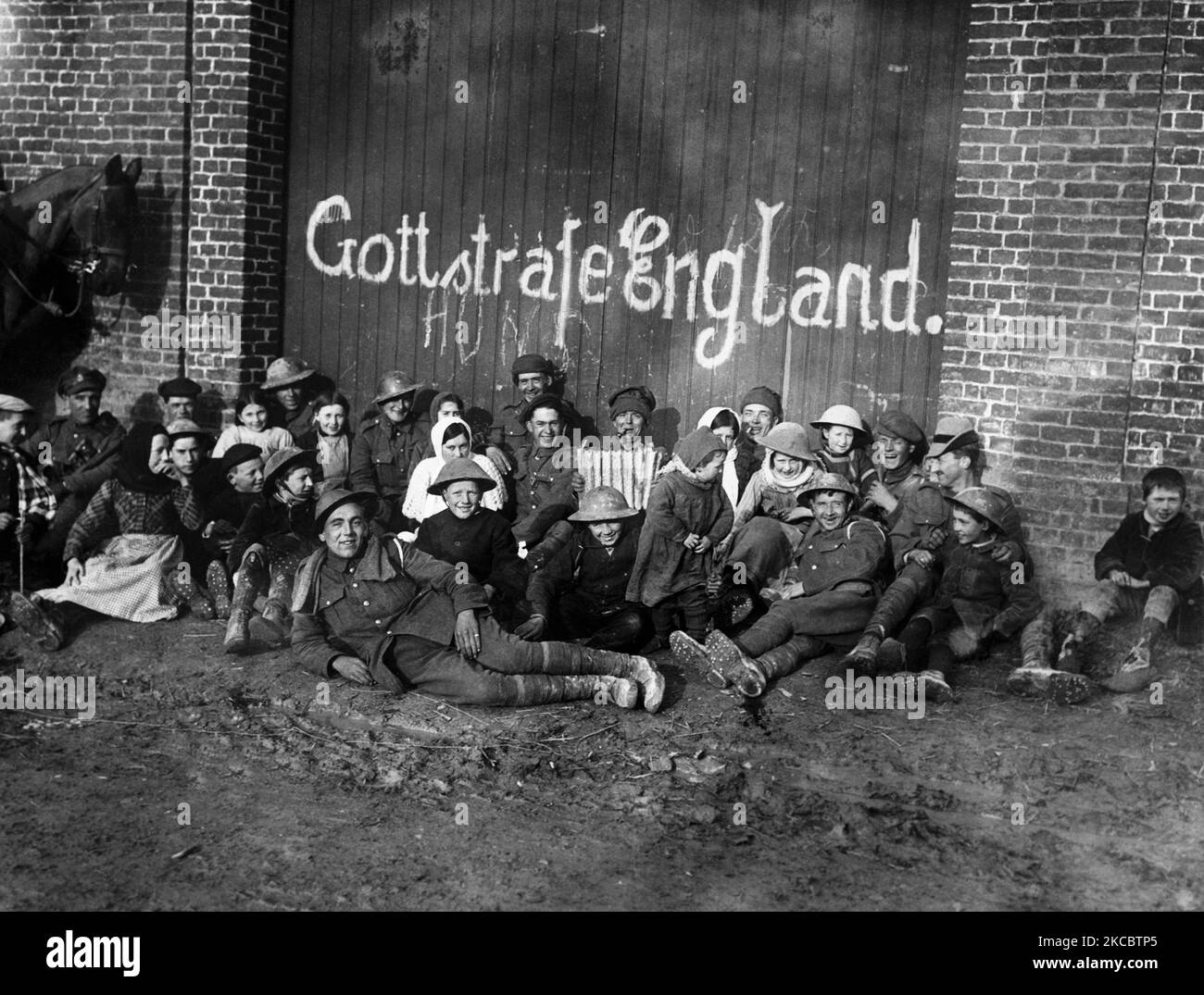 Soldati, donne e bambini britannici fuori da un edificio con graffiti tedeschi durante la prima guerra mondiale Foto Stock
