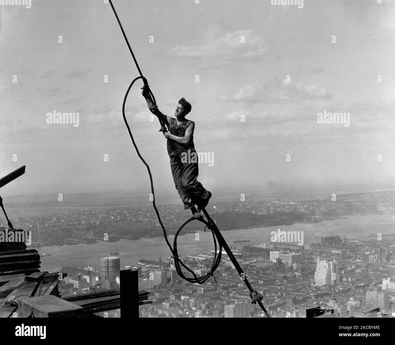 Un lavoratore dell'acciaio penzolante in un aggraziato sangfroide durante la costruzione dell'Empire state Building, 1930. Foto Stock