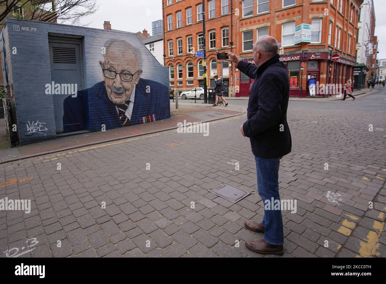 Un uomo scatta una fotografia un murale dipinto dall'artista grafitti Akse P19 raffigurante il capitano Sir Tom Moore nel centro di Manchester. (Foto di Giannis Alexopoulos/NurPhoto) Foto Stock