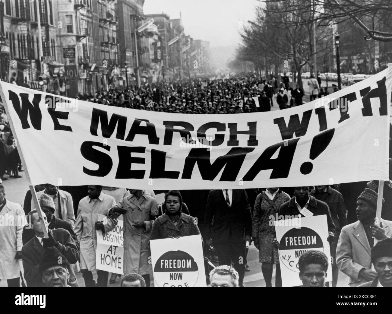 Marchers che trasportano una bandiera su una strada in Harlem, New York City, 1965. Foto Stock