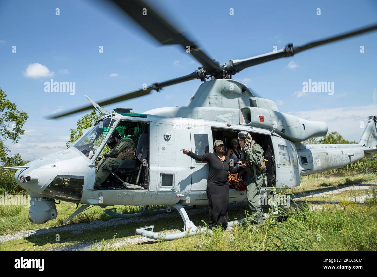 Una marina statunitense guida una famiglia a bordo di un elicottero UH-1Y durante una missione di salvataggio in uragano. Foto Stock